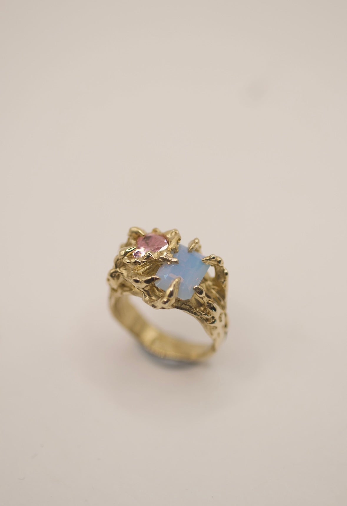 Handmade 9ct gold or sterling silver ring featuring an emerald-cut lab-grown opal with blue hues and a light pink cubic zirconia heart, set with delicate claws.