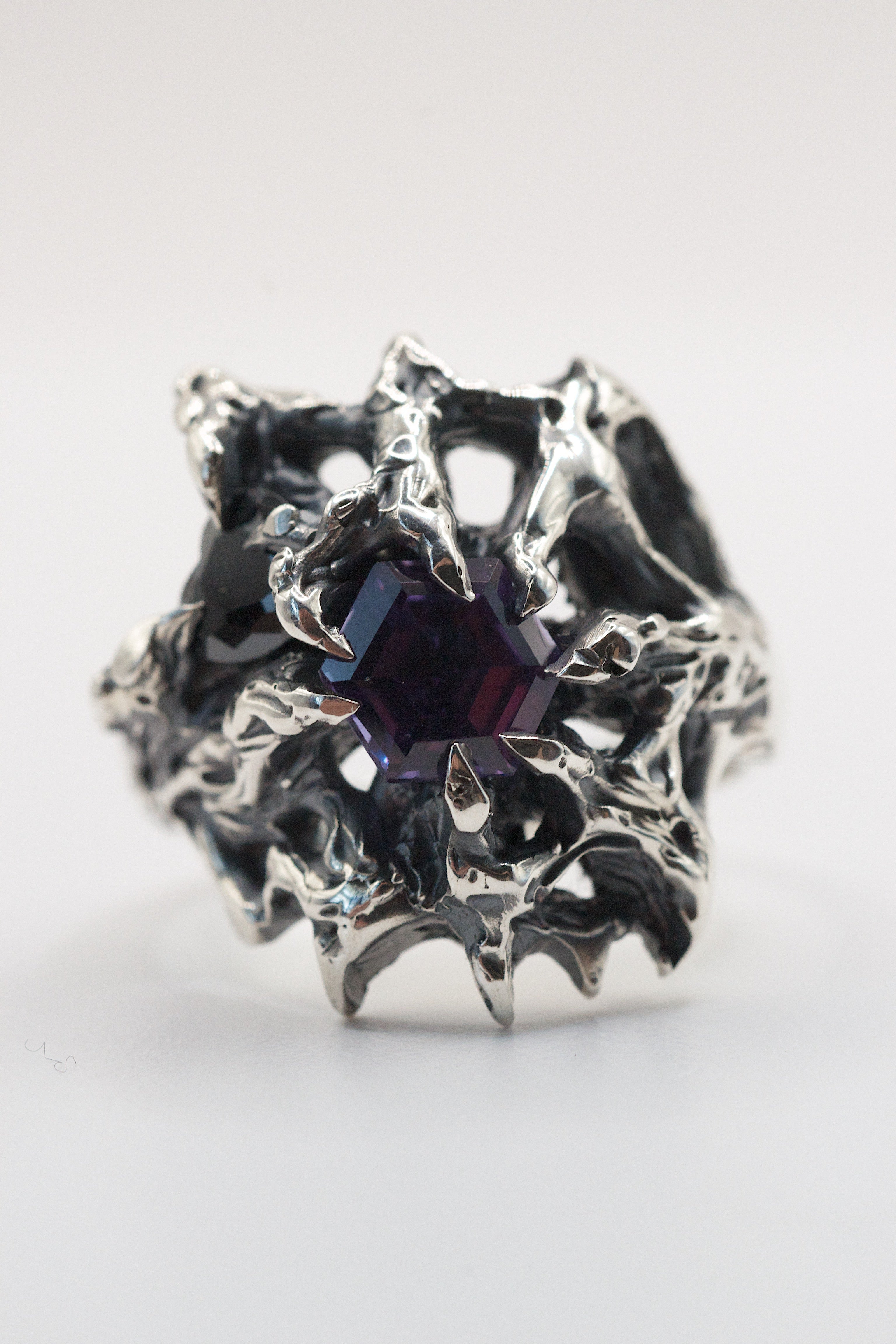 Hand-sculpted silver ring featuring a hexagon-cut alexandrite and a heart-shaped cubic zirconia, held by gothic-style claws.