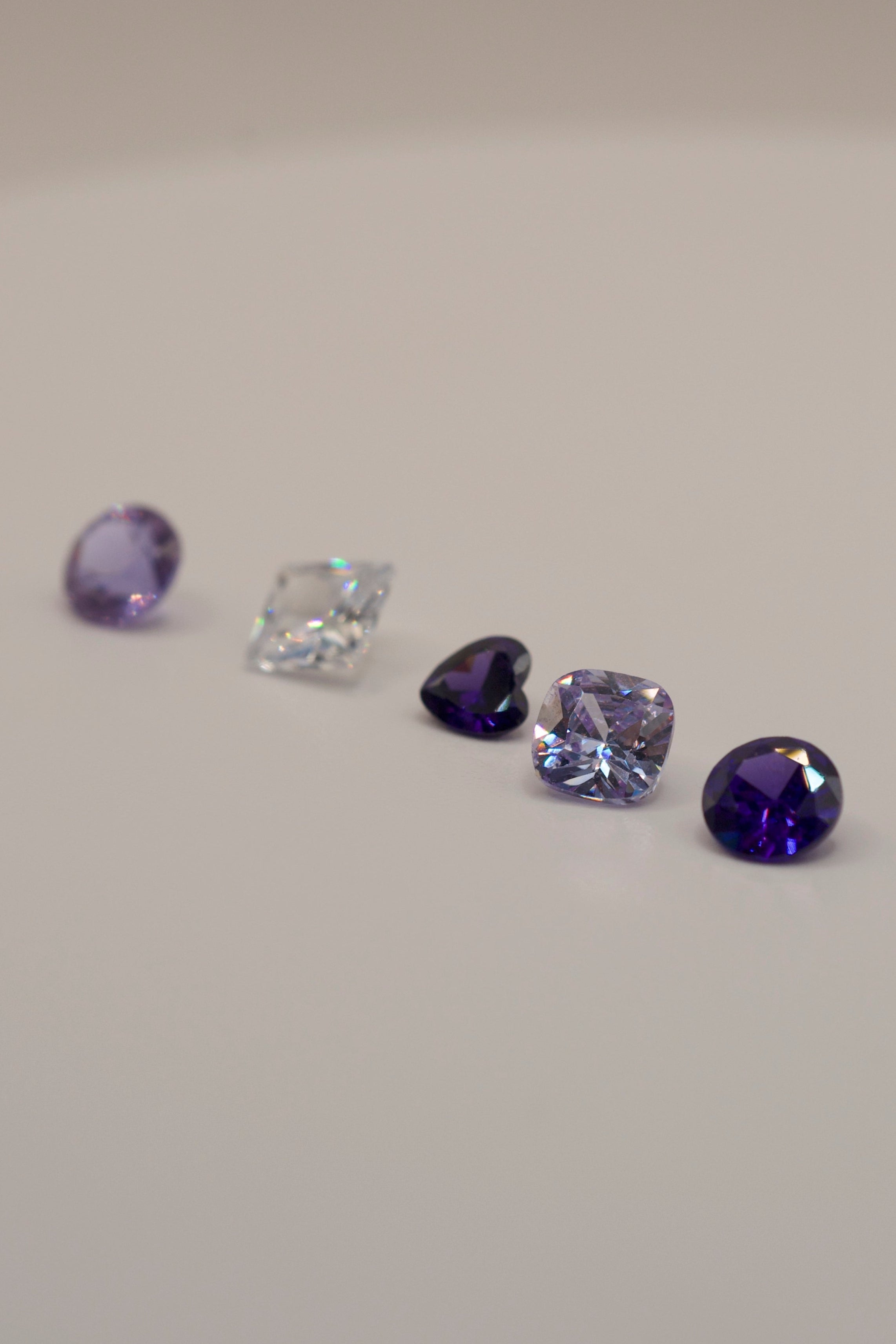 Gemstones designed for cast in place wax carving. Selection includes purple and clear faceted cuts, ideal for unique silver and gold jewellery making.