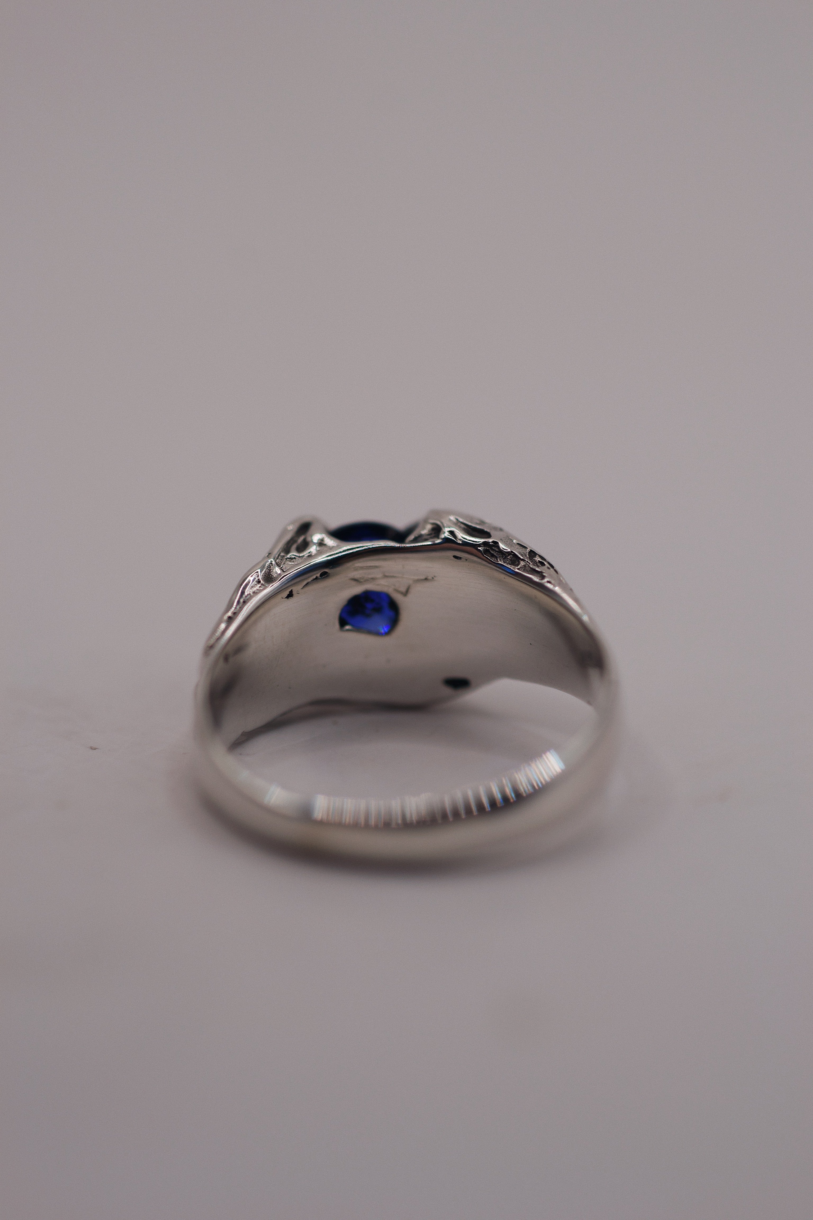 Raw and detailed silver ring designed with gothic influence, featuring a round sapphire and made using the lost wax casting process.