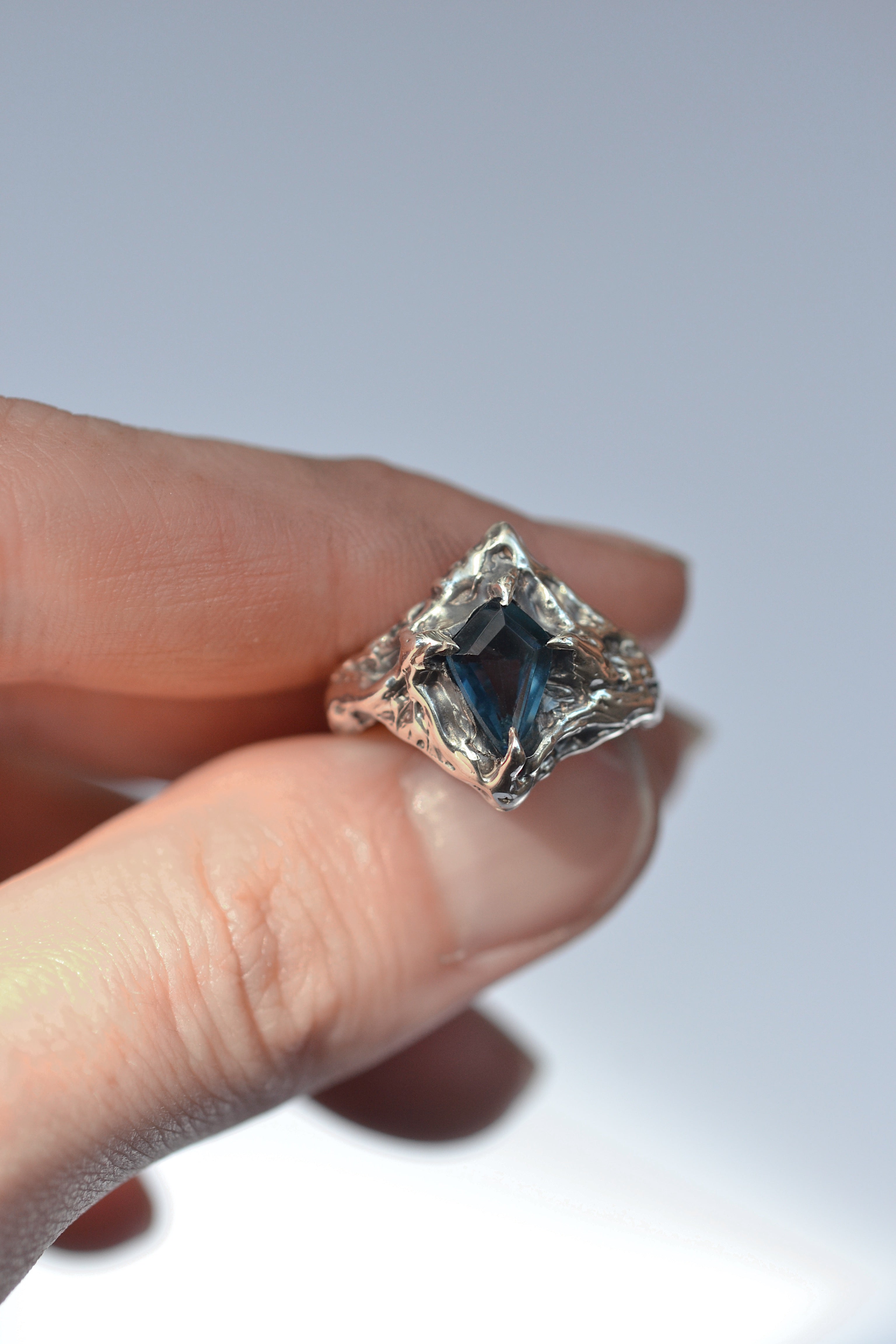 This one-of-a-kind lost wax jewelry design showcases a stunning 9x6mm kite-cut topaz, set in recycled 925 sterling silver with intricate detailing and a moody patina finish.