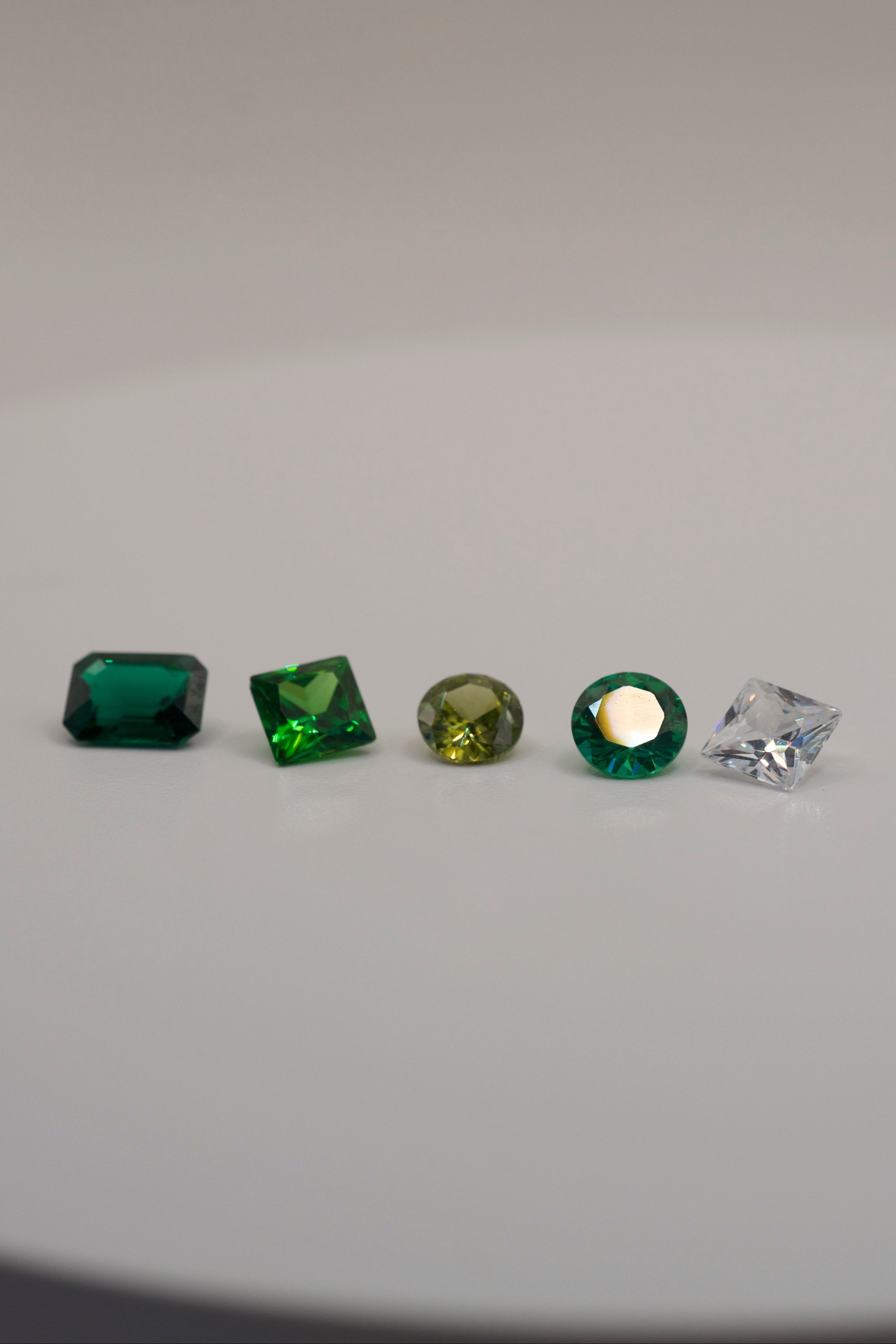 Gemstones for cast in place wax carving jewellery — emerald cut green, square green, round olive, round teal, and princess cut clear stone.