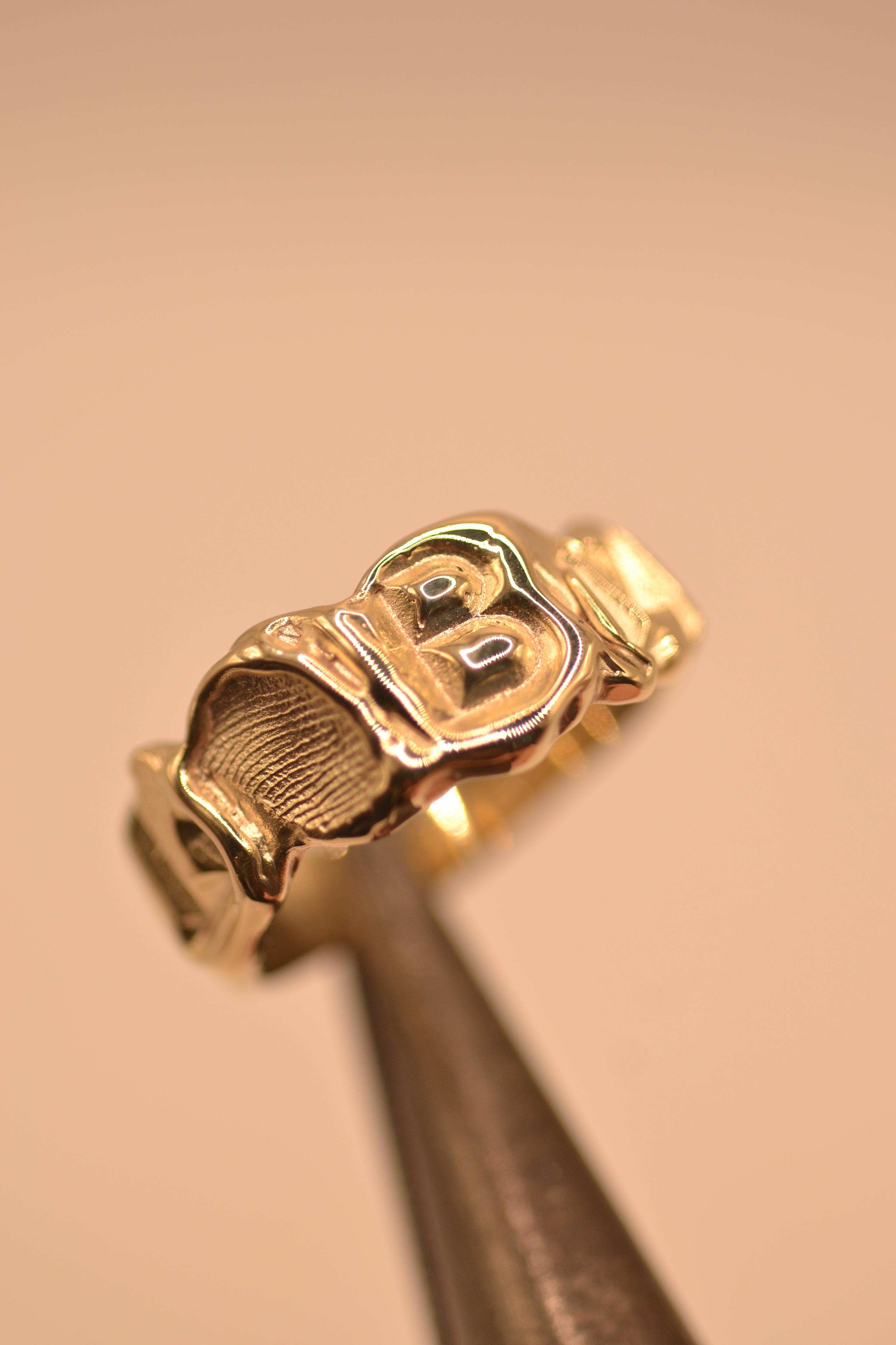 Handmade gold initial ring worn on hand showing molten lost wax casting texture and personalised letters