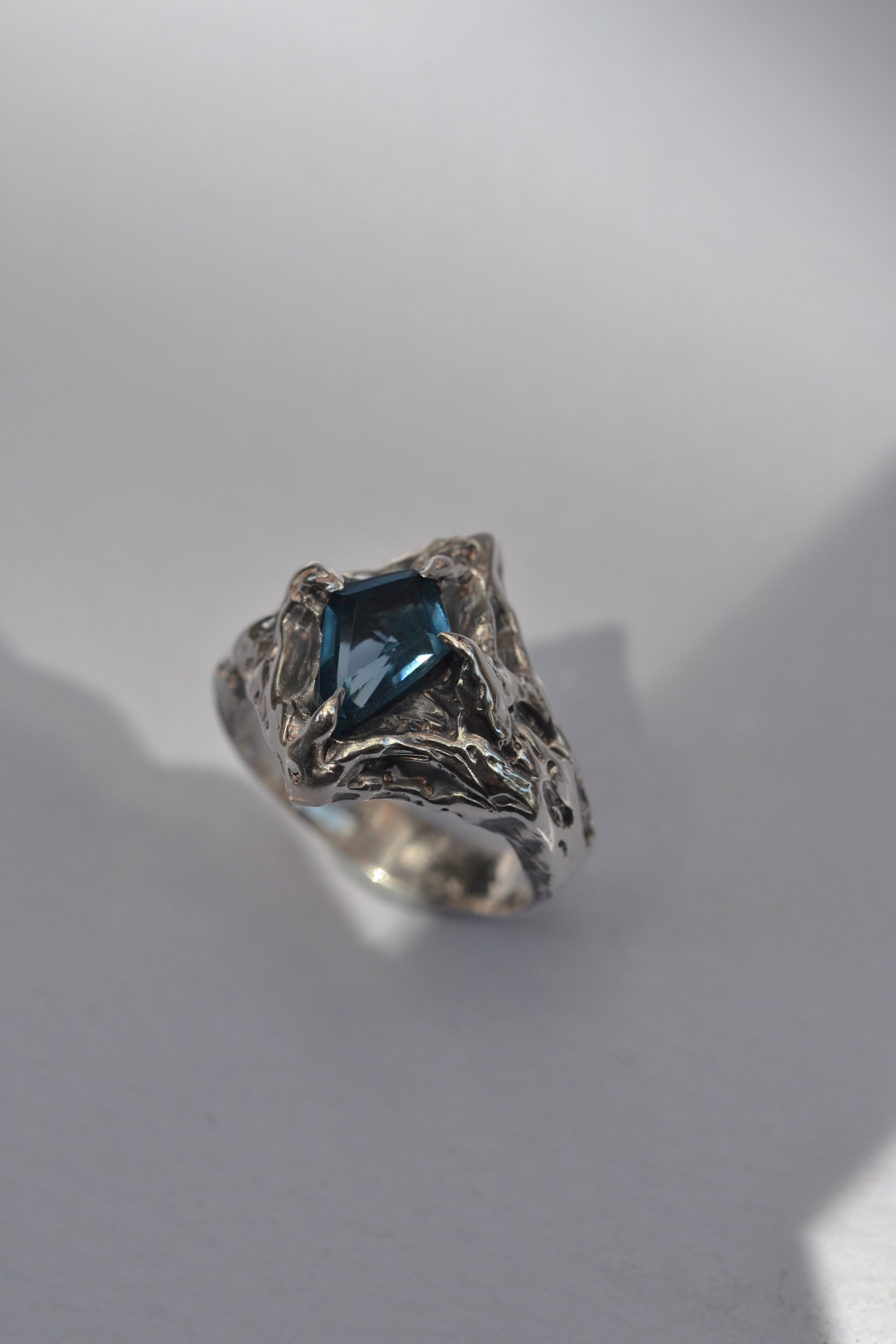 A unique lost wax-carved ring featuring a natural kite-cut topaz set in recycled 925 sterling silver with an ethereal darkened patina. A blend of gothic romance and timeless artistry.