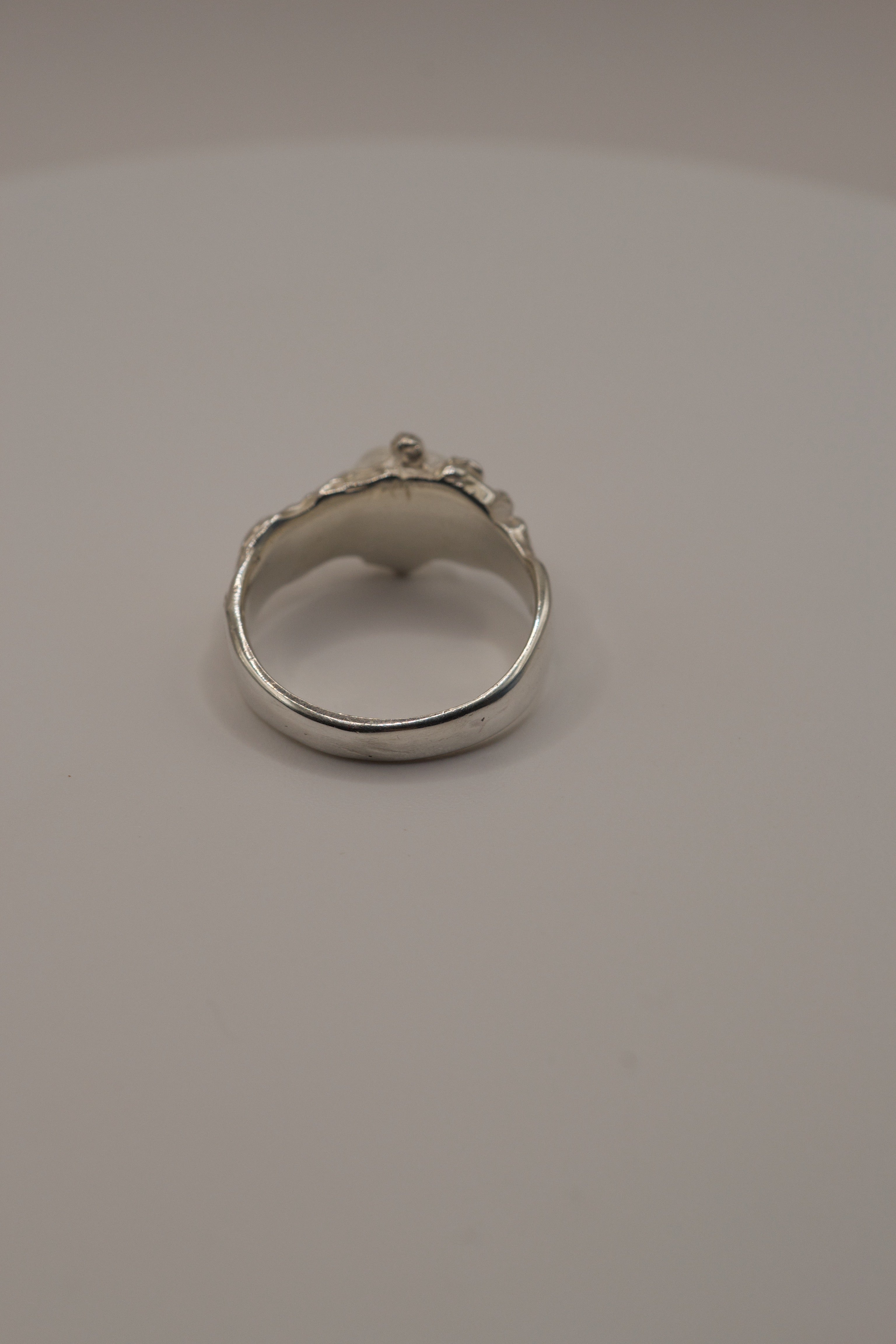 Handmade lost wax jewellery ring in sterling silver, molten textured band with irregular clear quartz crystal, back view.
