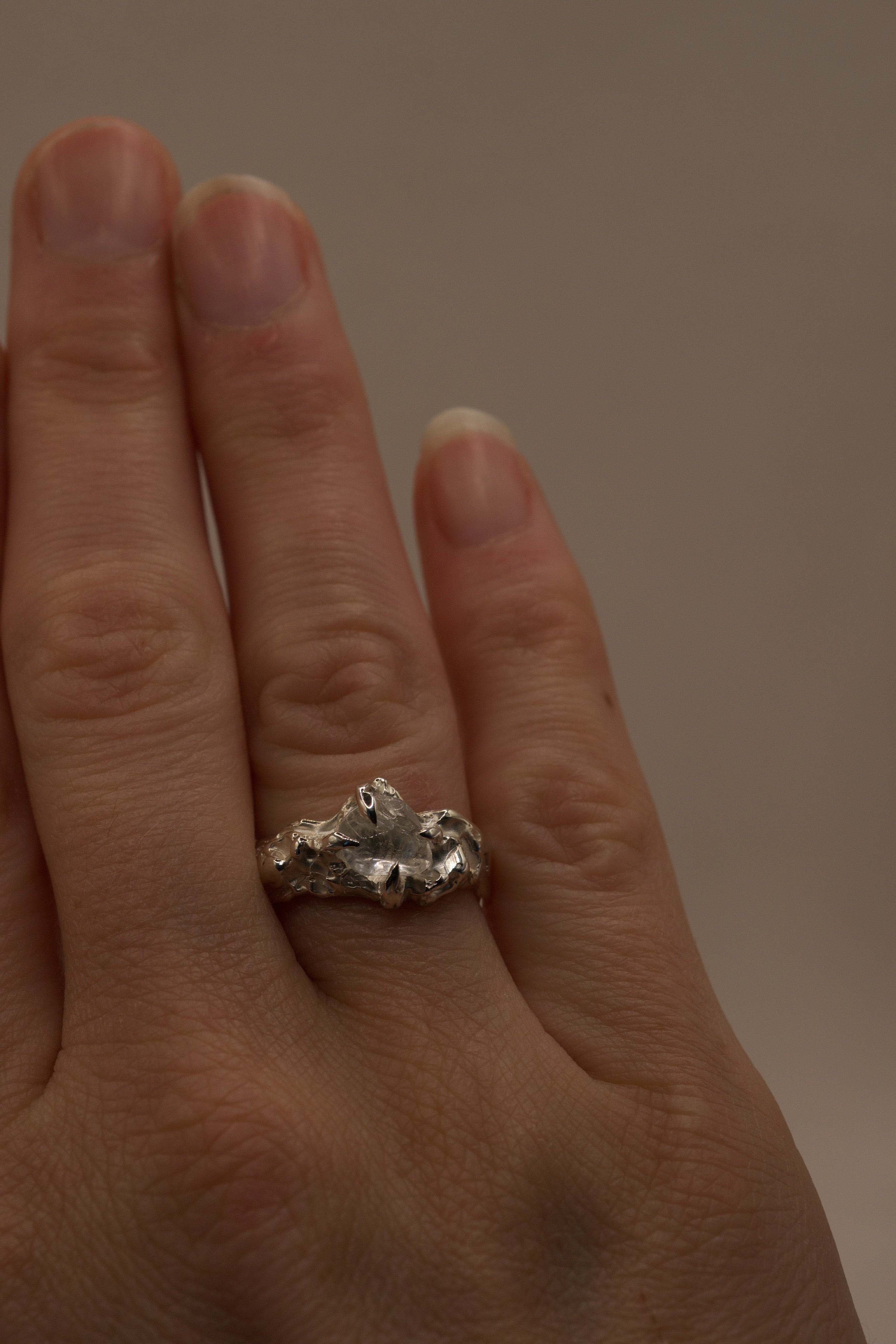 Full hand shot showing handmade lost wax sterling silver ring, organic molten band with raw irregular clear quartz gemstone.