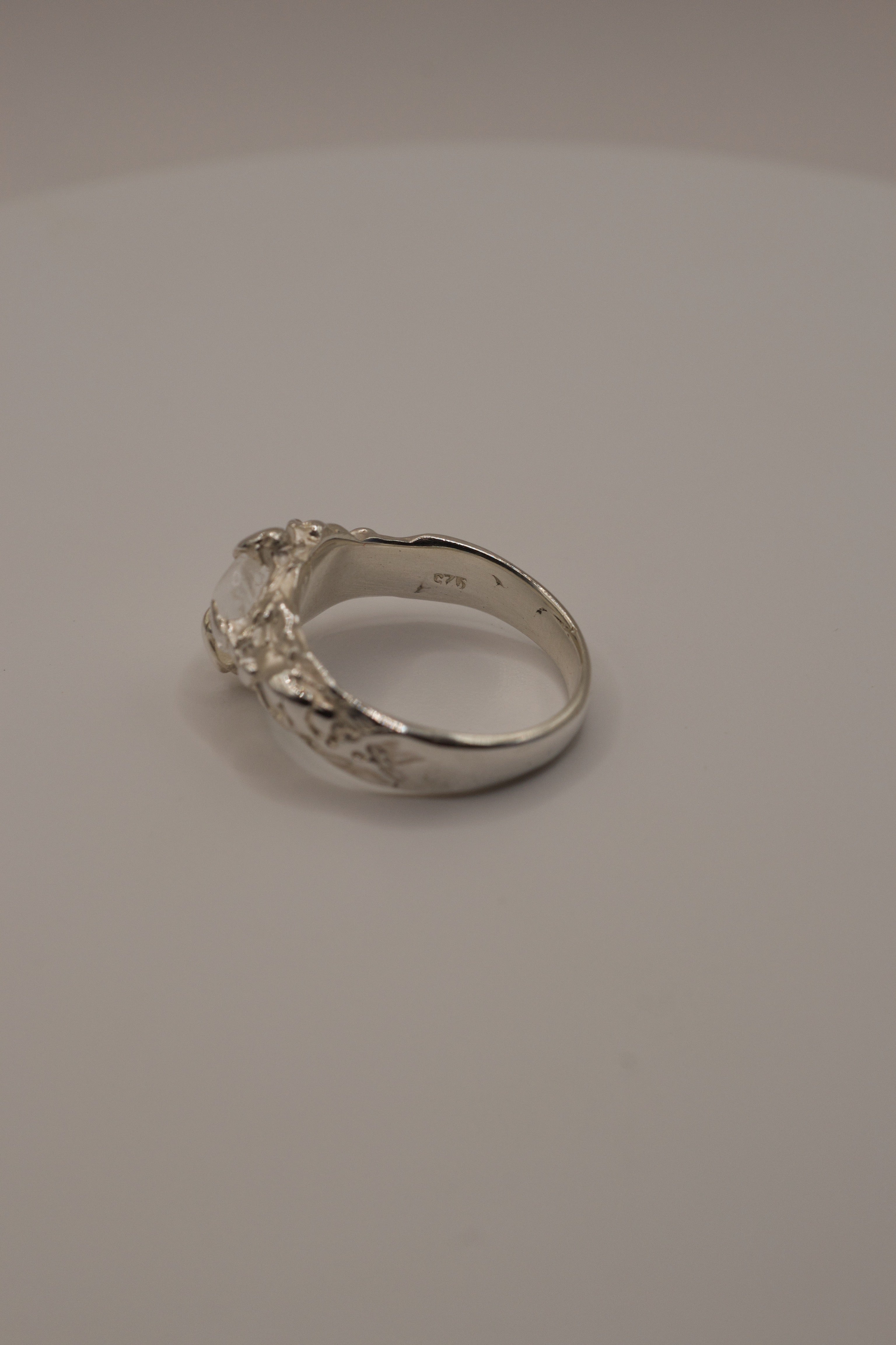 Handmade lost wax sterling silver ring with organic molten claws holding raw irregular clear quartz, rear profile view.