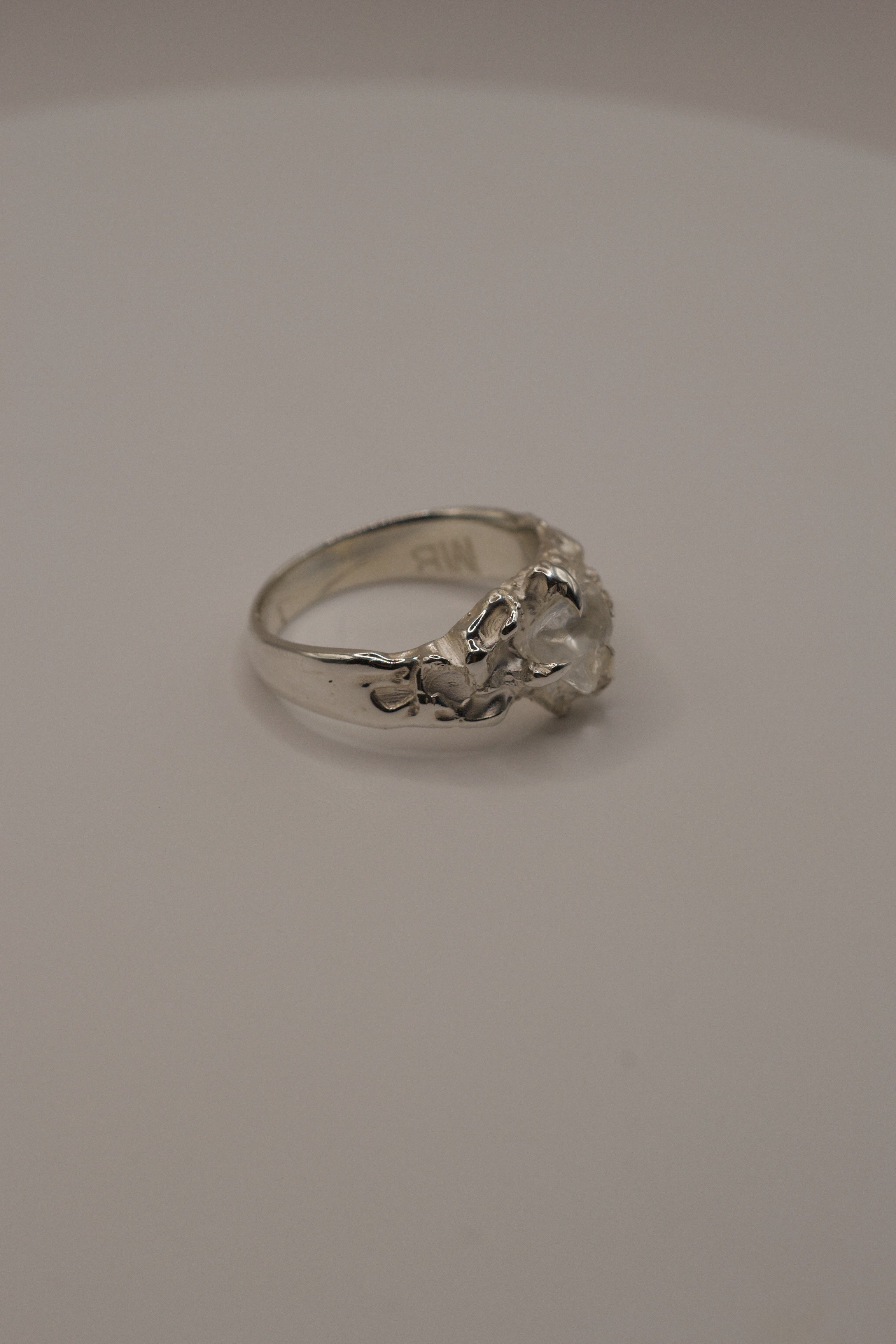 Handmade lost wax sterling silver ring, side profile showing molten organic band and irregular clear quartz crystal.