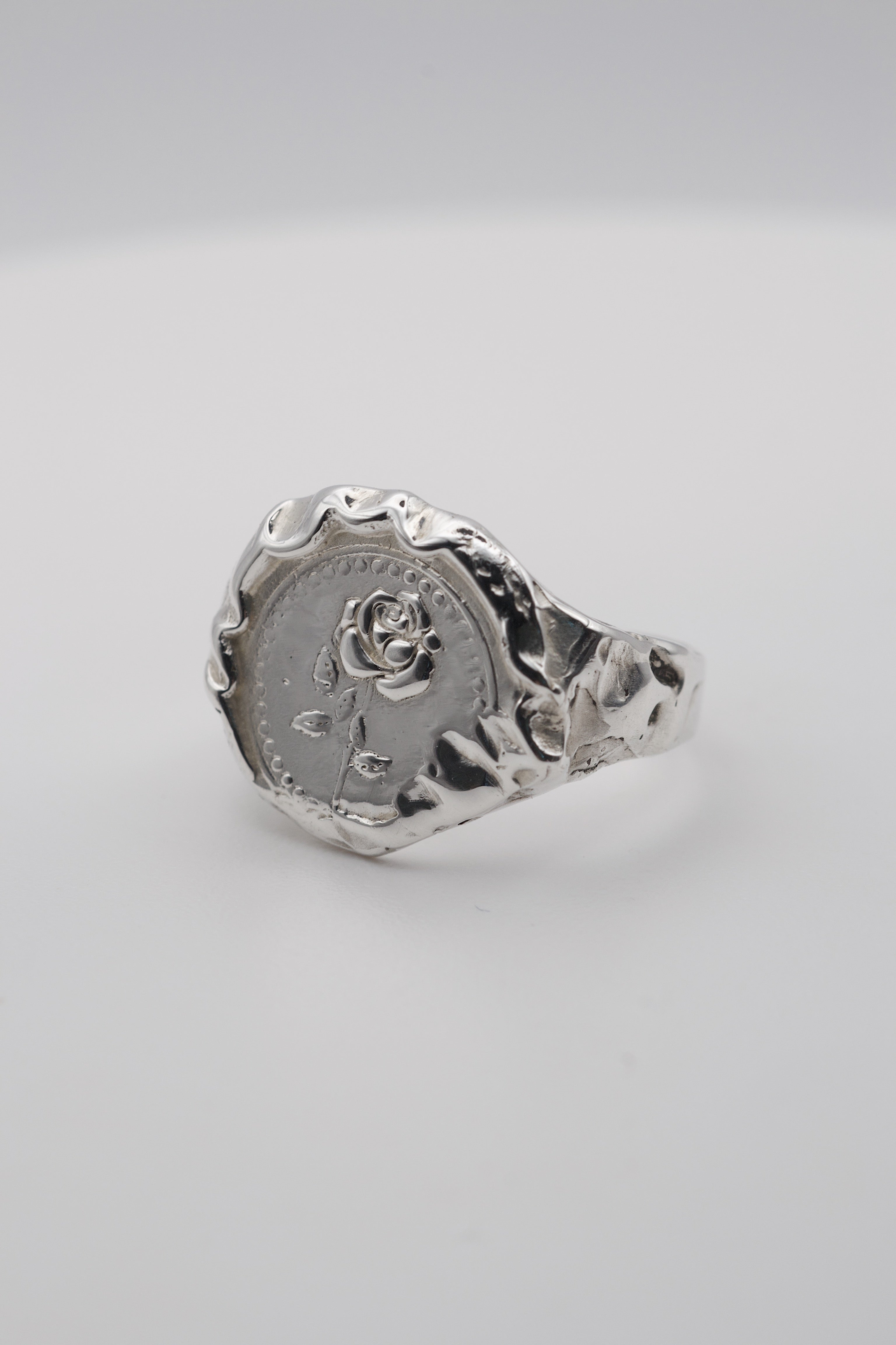 Handmade molten silver signet ring created using the lost wax technique, featuring an embossed rose design and organic molten texture edges in an alternative gothic style.
