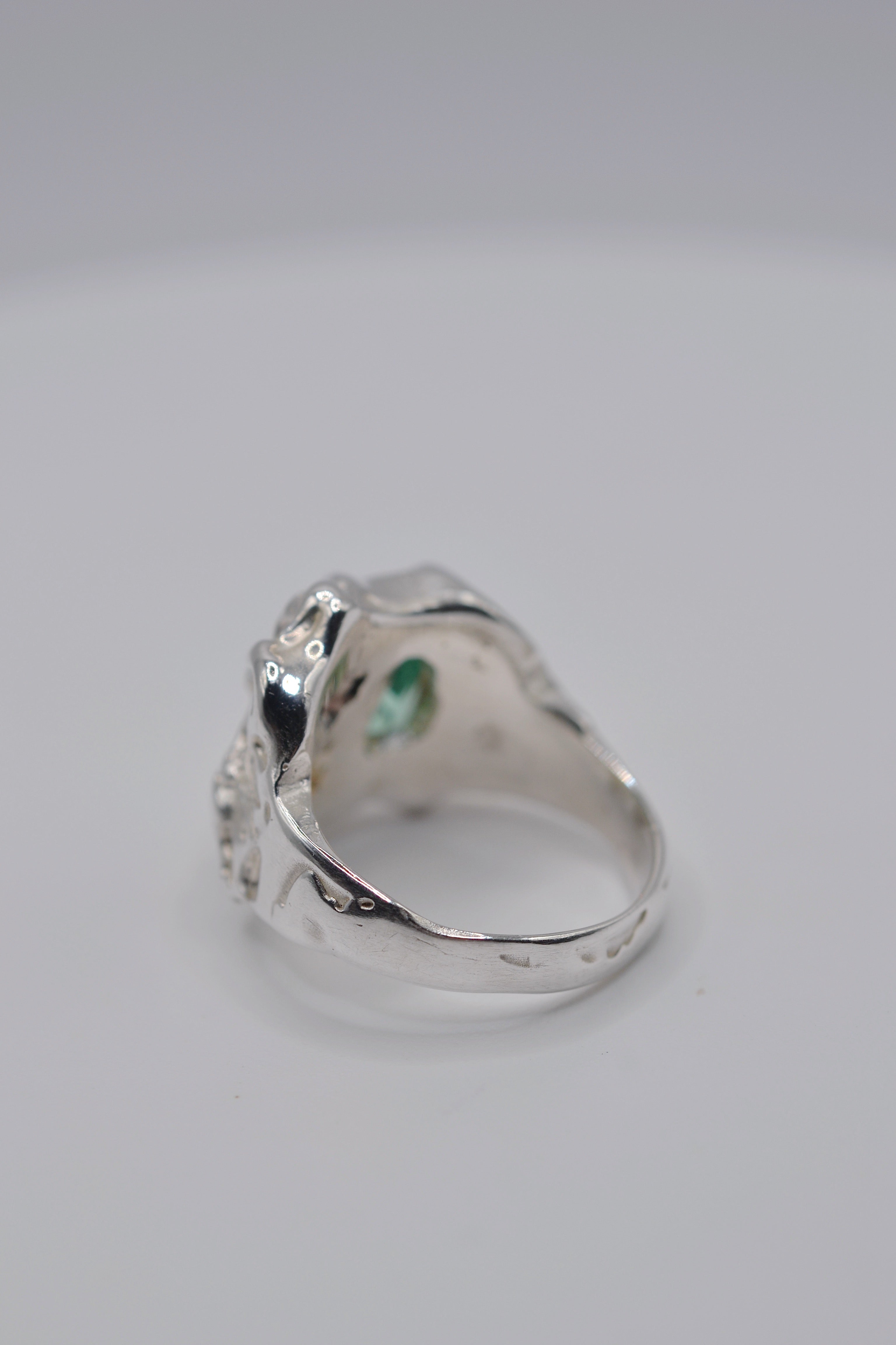 Angled view of the Mirage ring. Handmade organic silver, sculpted using wax carving and lost wax casting. Lab-grown green tourmaline, pink heart CZ and yellow opal. Metal Bones Jewellery.