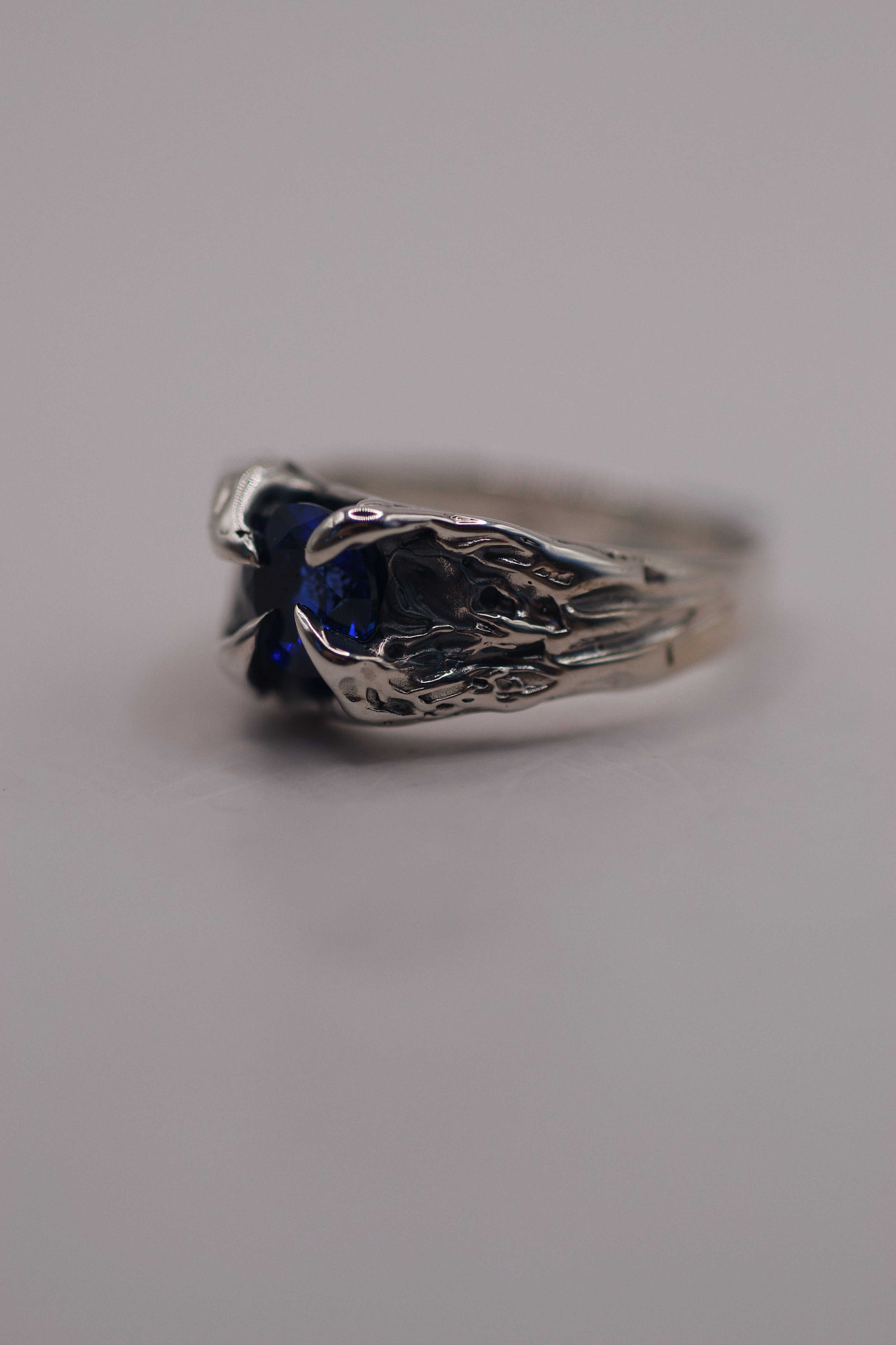 Unique silver ring with a claw-set round sapphire, sculpted by hand using the lost wax casting technique with gothic design elements.