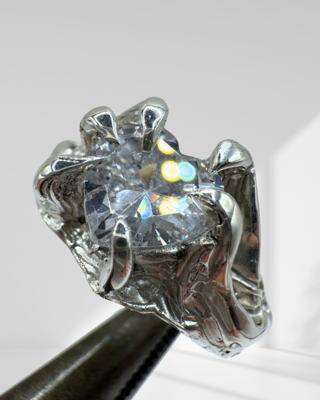Lost wax carved sterling silver ring with gothic claws, molten texture, and a heart-shaped clear cubic zirconia crystal in an organic, handmade setting.
