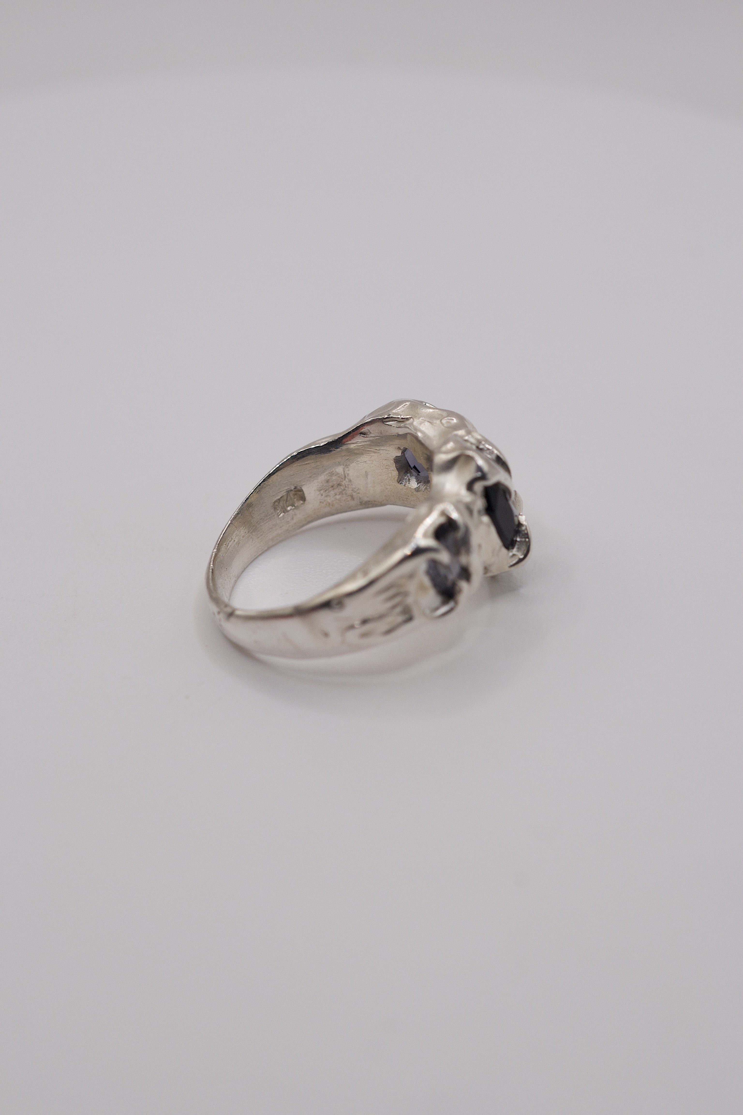 Rear view of organic handmade sterling silver ring showing the hole behind the inner band and holes behind the stones in the band.
