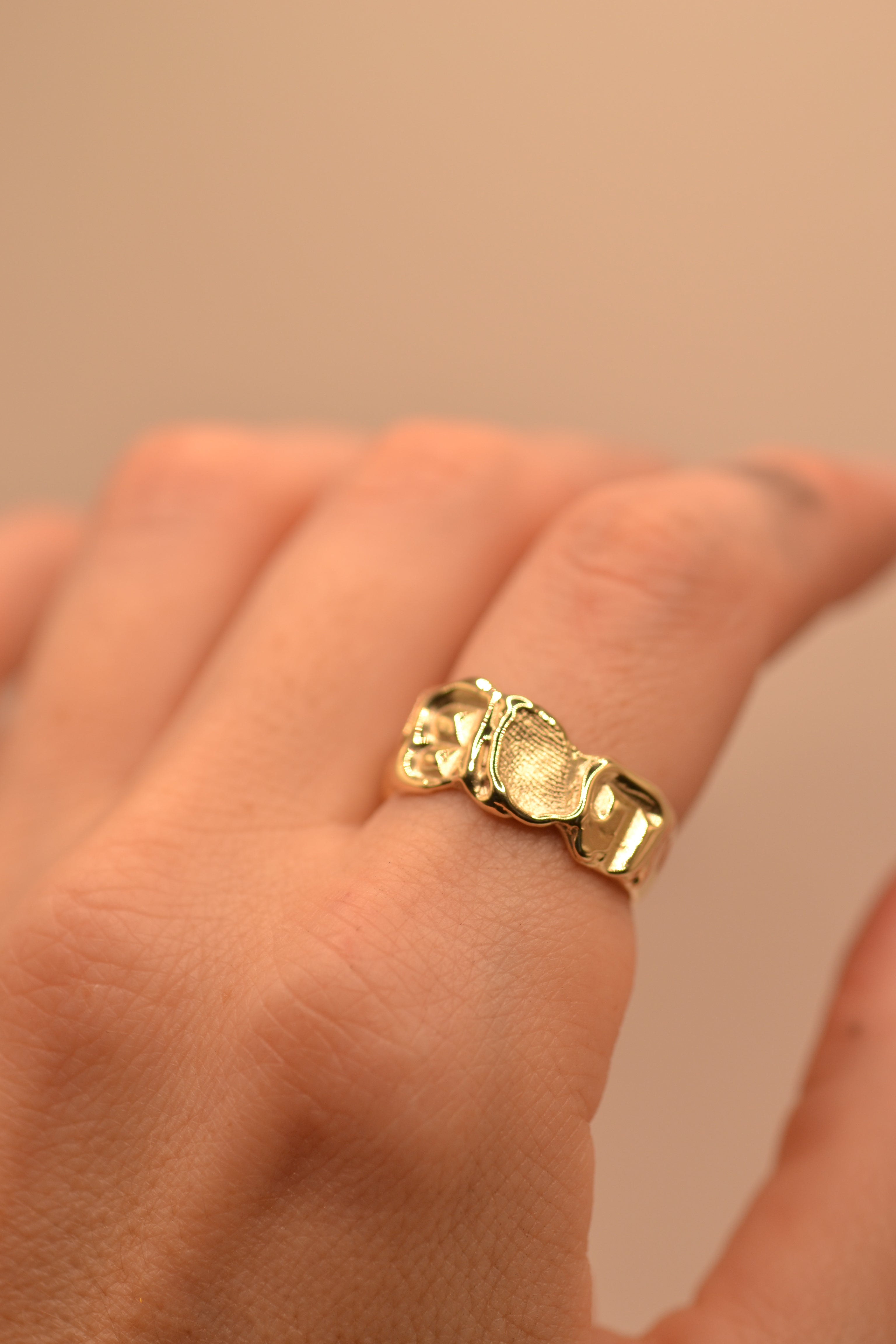 Side view of lost wax cast gold initial ring on finger showing band depth and organic texture