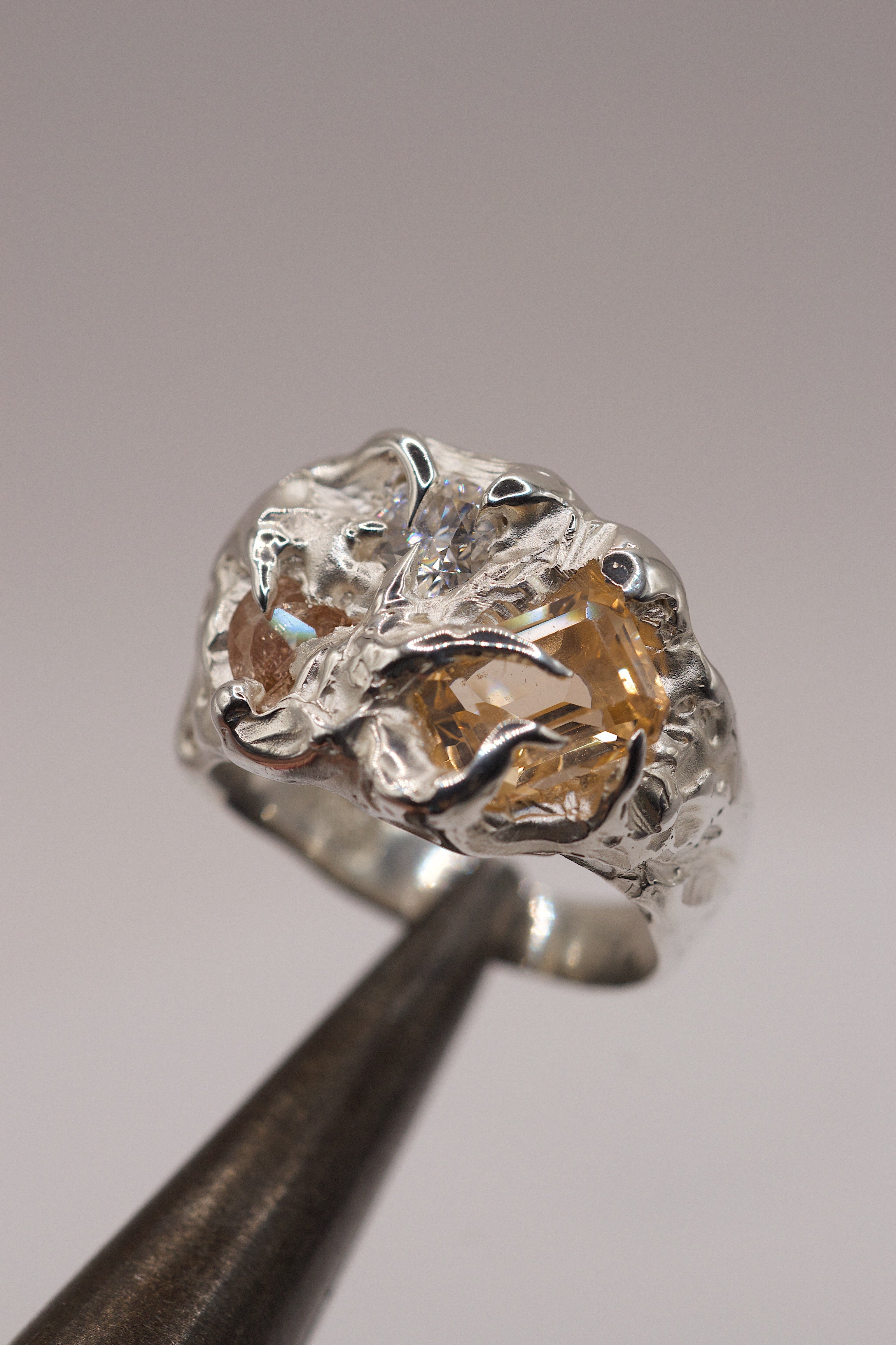 Heavily textured organic silver ring handmade with lost wax technique featuring multiple claws and citrine gemsotnes.