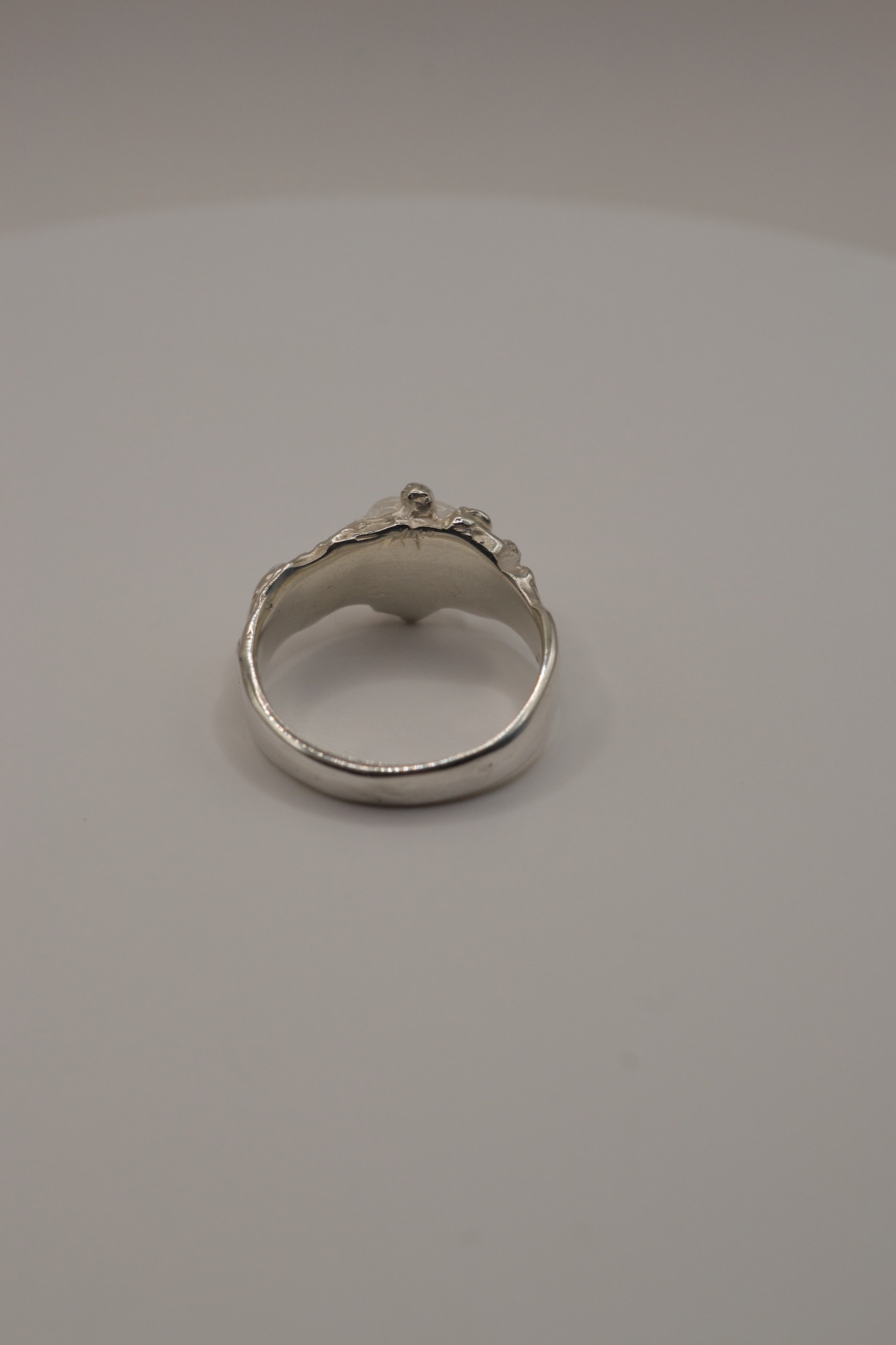 Rear angle of handmade lost wax sterling silver ring, organic molten band with irregular clear quartz gemstone.