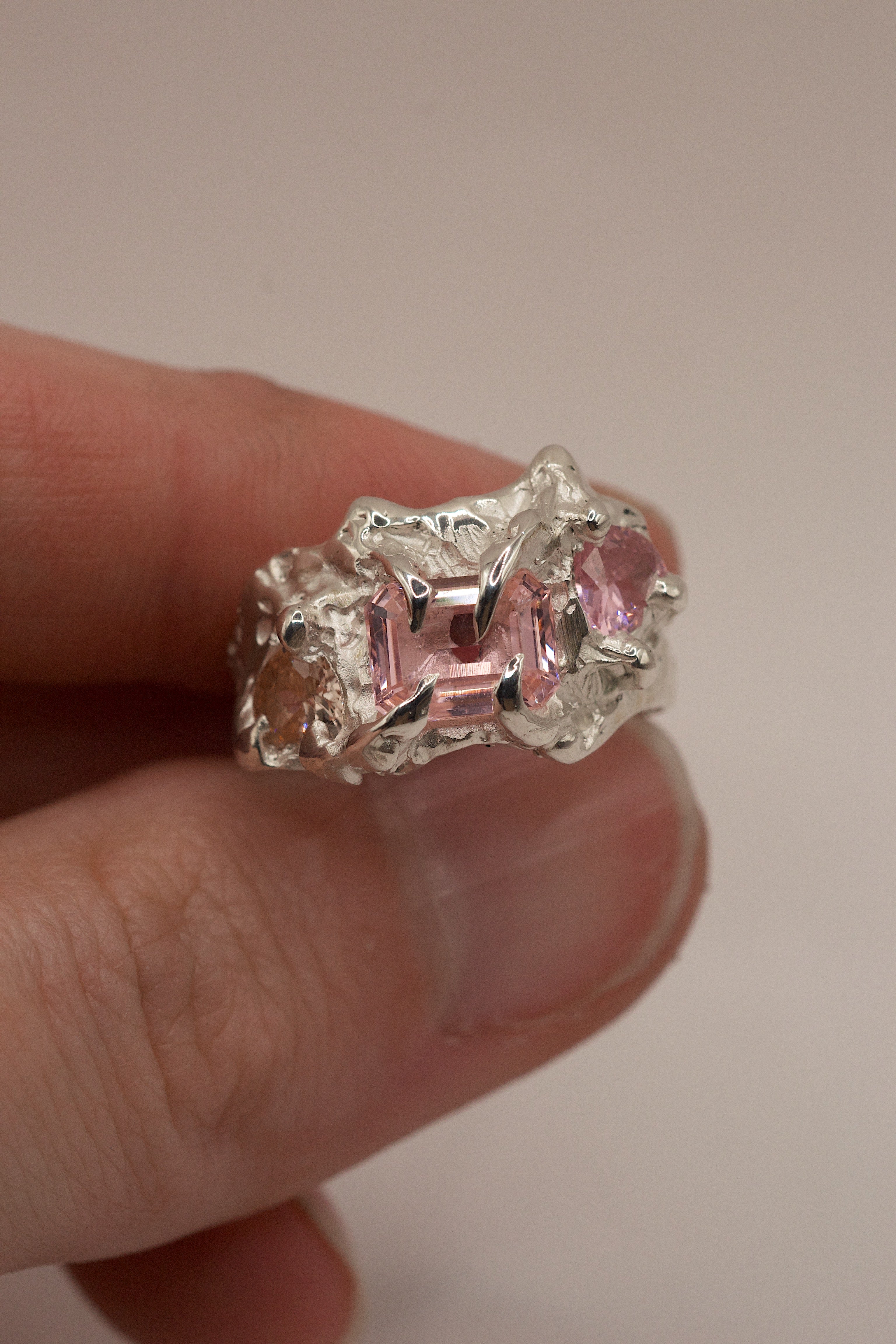 Lost wax cast silver Blossom Ring held in hand sculptural alternative engagement ring with pink tourmaline and organic molten silver setting