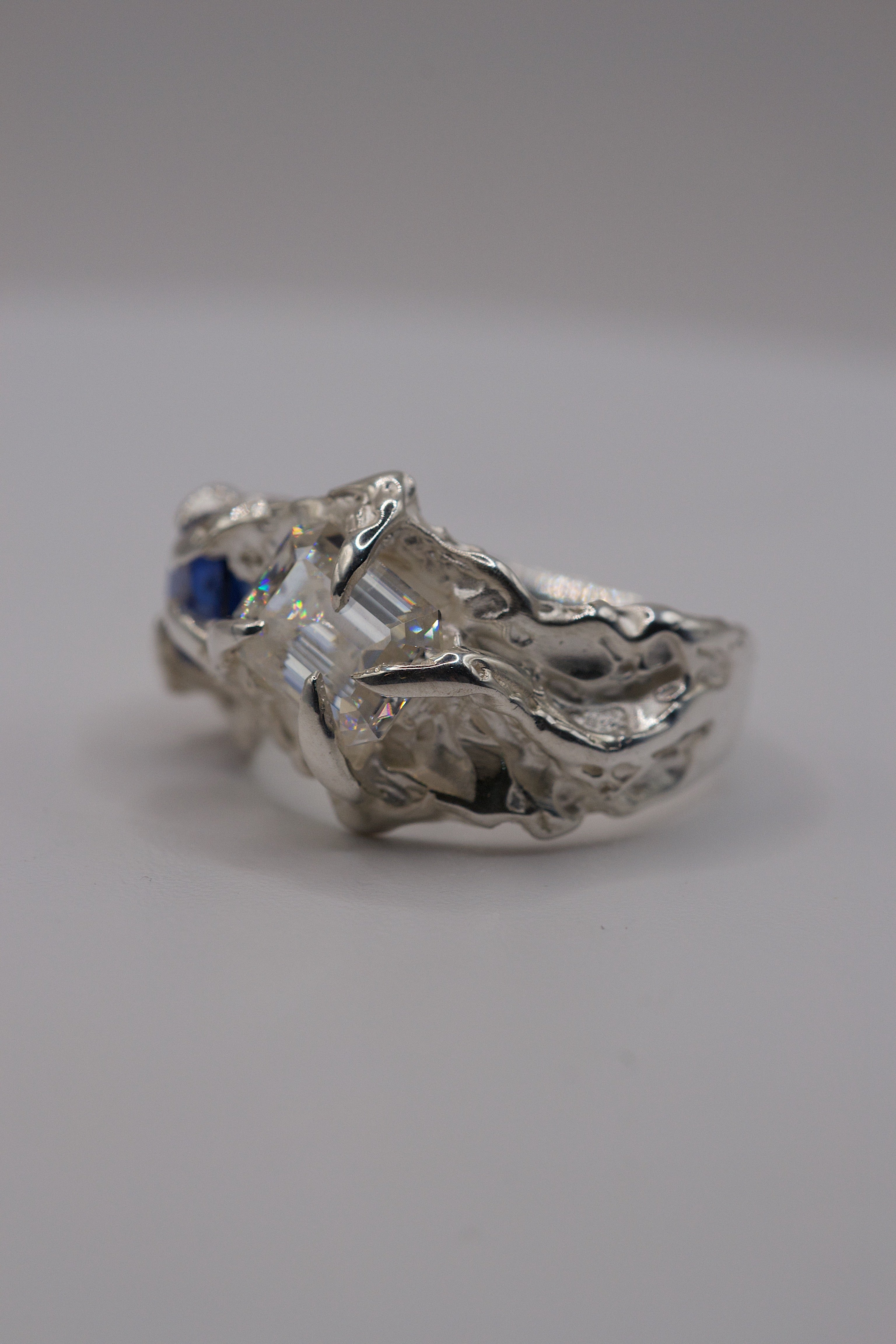 Front view of the Blue Crush Ring showing natural blue sapphire and white moissanite set within organic molten sterling silver handmade using the lost wax technique
