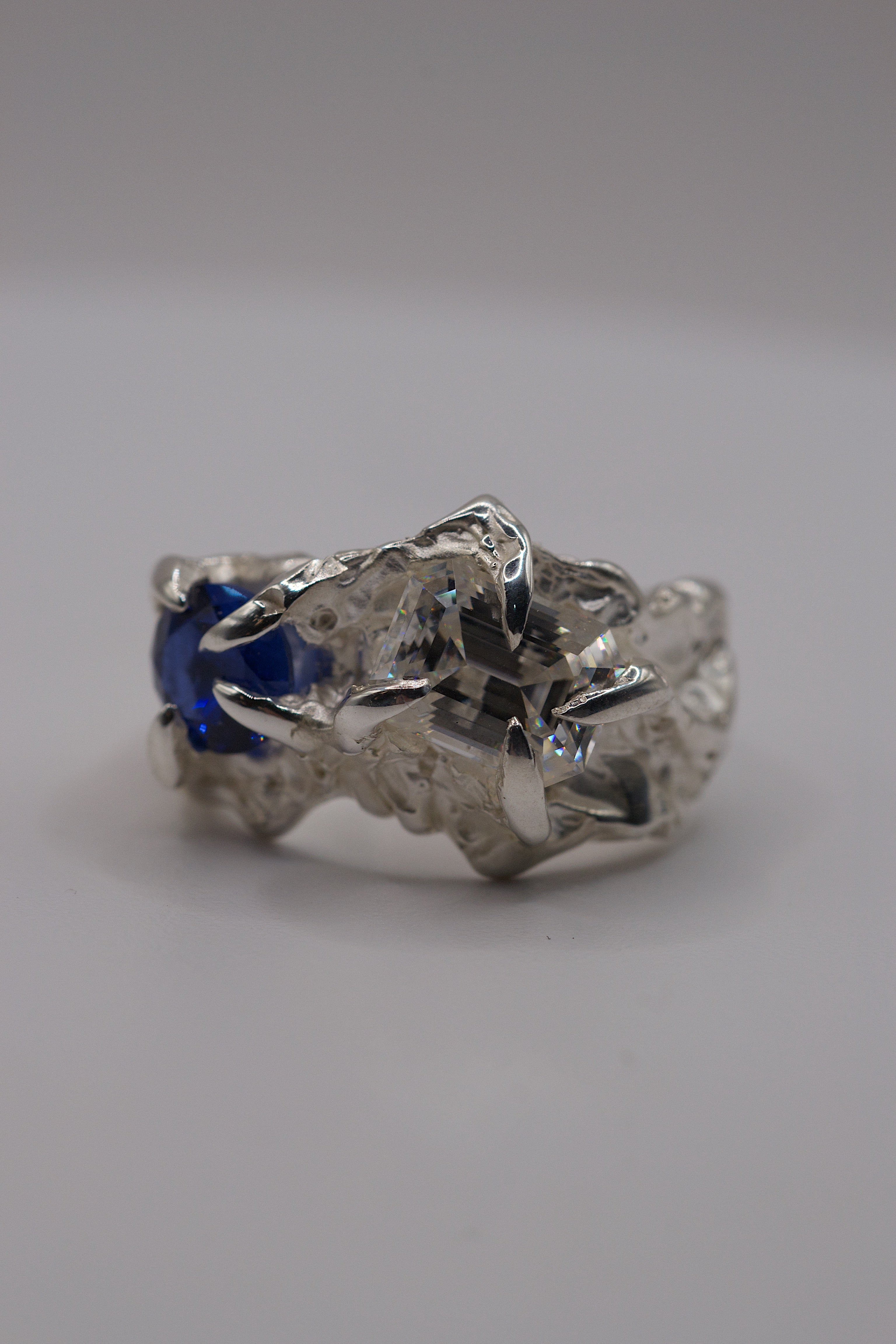 Side angle of the Blue Crush Ring showing organic recycled sterling silver band with blue sapphire and moissanite setting