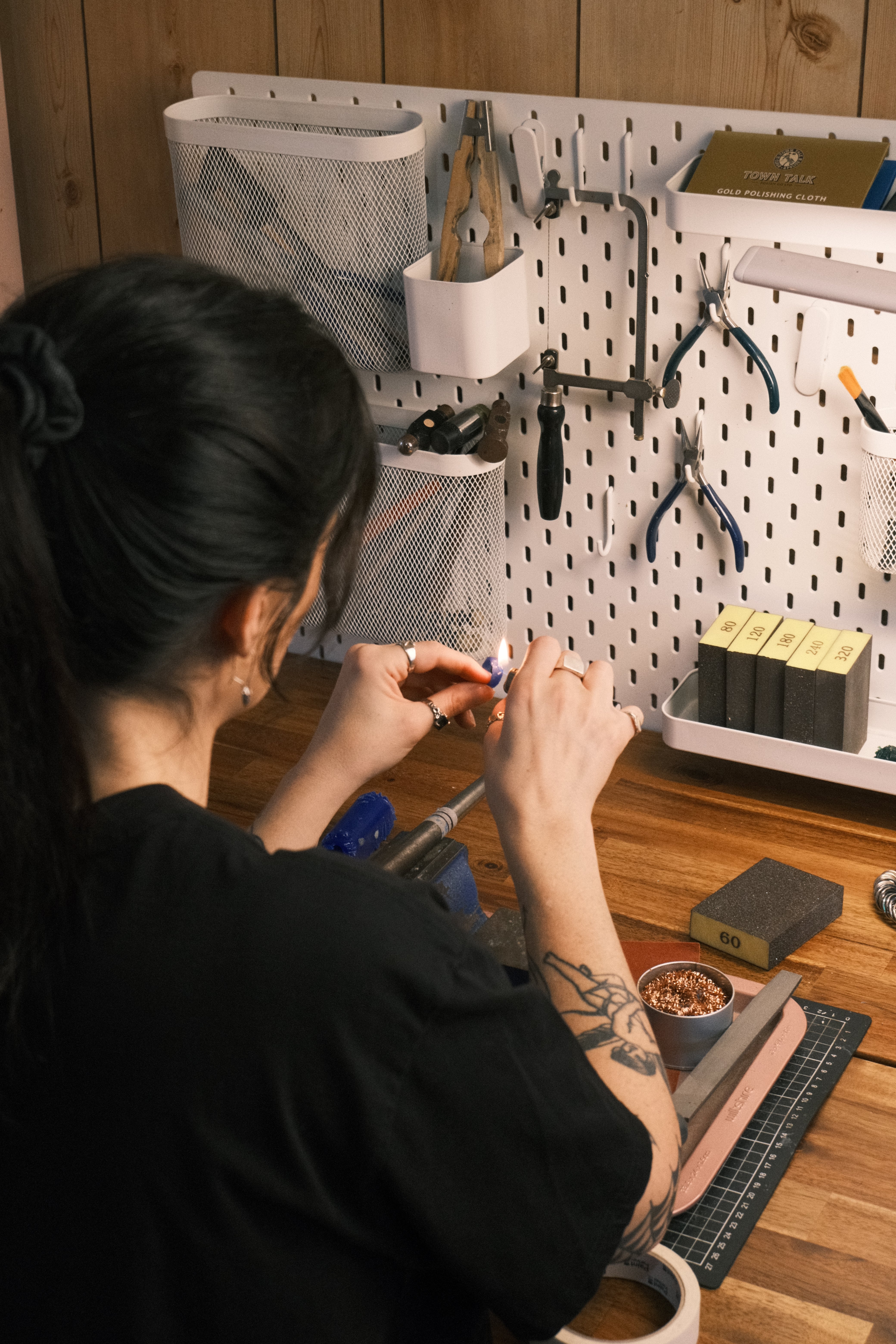 Cassandra Djodan jeweller and lost wax jewellery maker working at her studio bench with jewellery tools on pegboard, making handmade silver jewellery using the wax carving technique