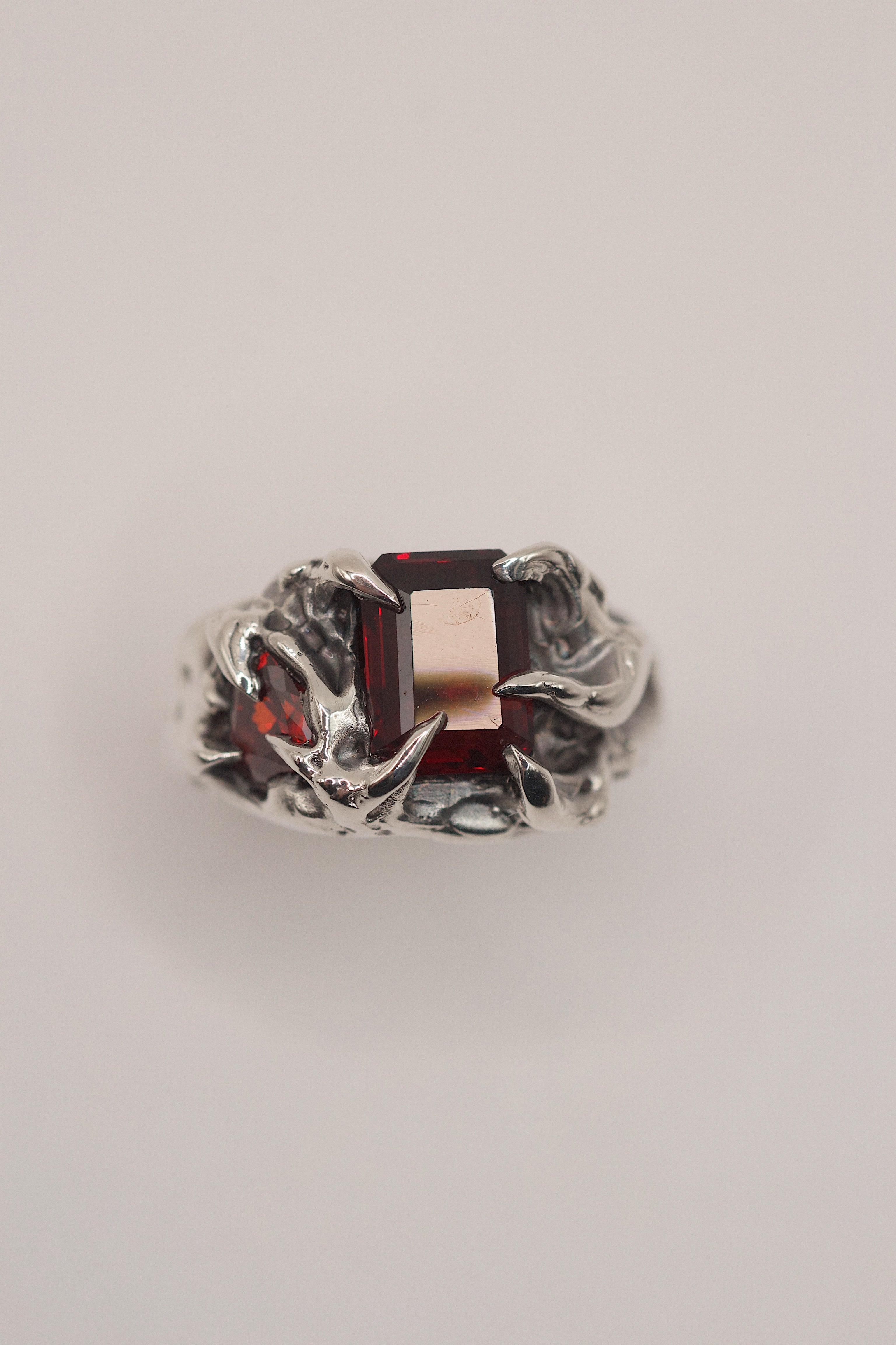 Handmade lost wax cast sterling silver ring with sharp organic claws holding red lab-grown garnet and red heart cubic zirconia, fierce alternative ring made using the wax carving technique