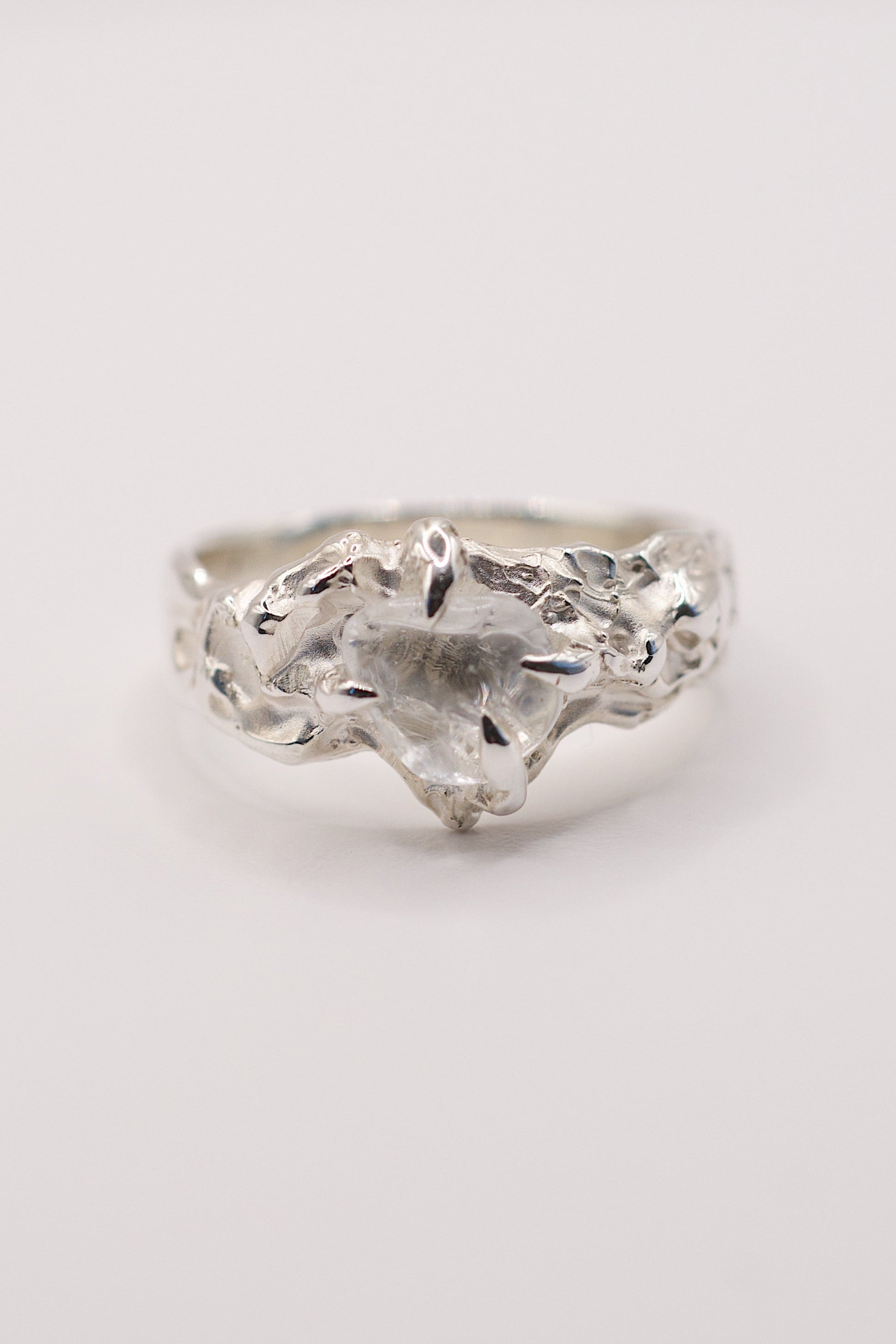 Handmade lost wax cast sterling silver ring with flowing organic silver wrapped around an irregular natural clear quartz, dreamlike sculptural ring made using the wax carving technique