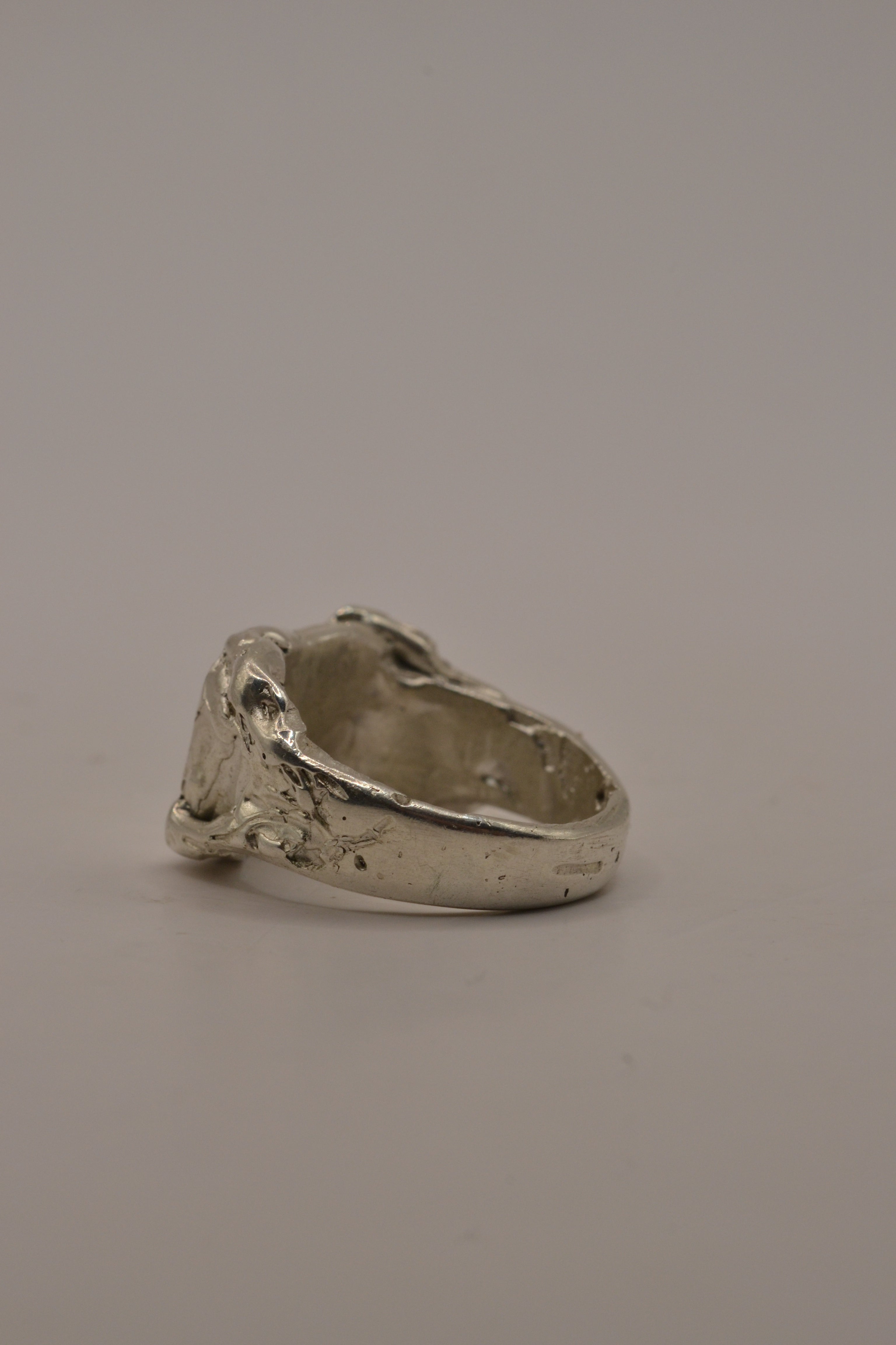 Side angle of the Concrete Ring showing raw textured sterling silver signet form and organic band handmade using lost wax casting technique