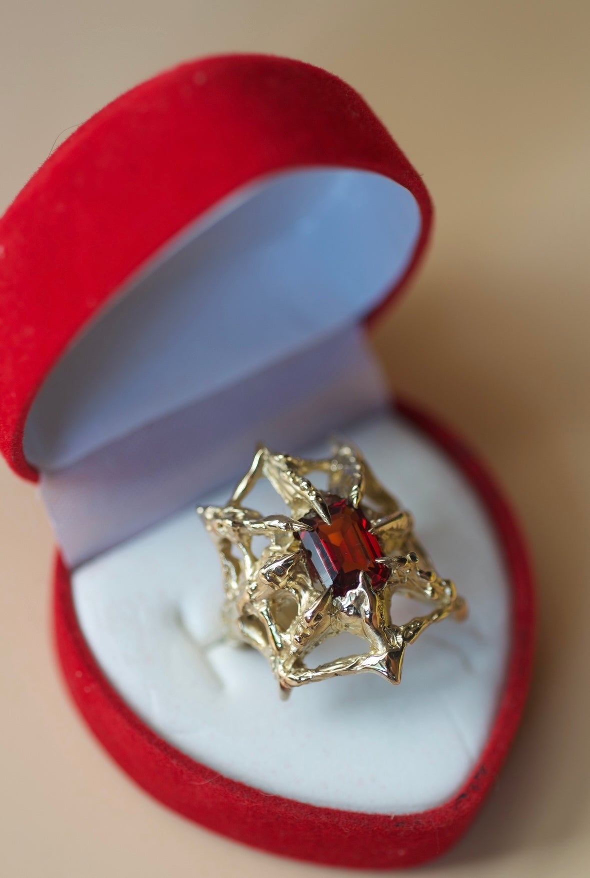 Lost wax cast gold Doom Ring in ring box with lab-grown red garnet and web structure design handmade using the wax carving technique