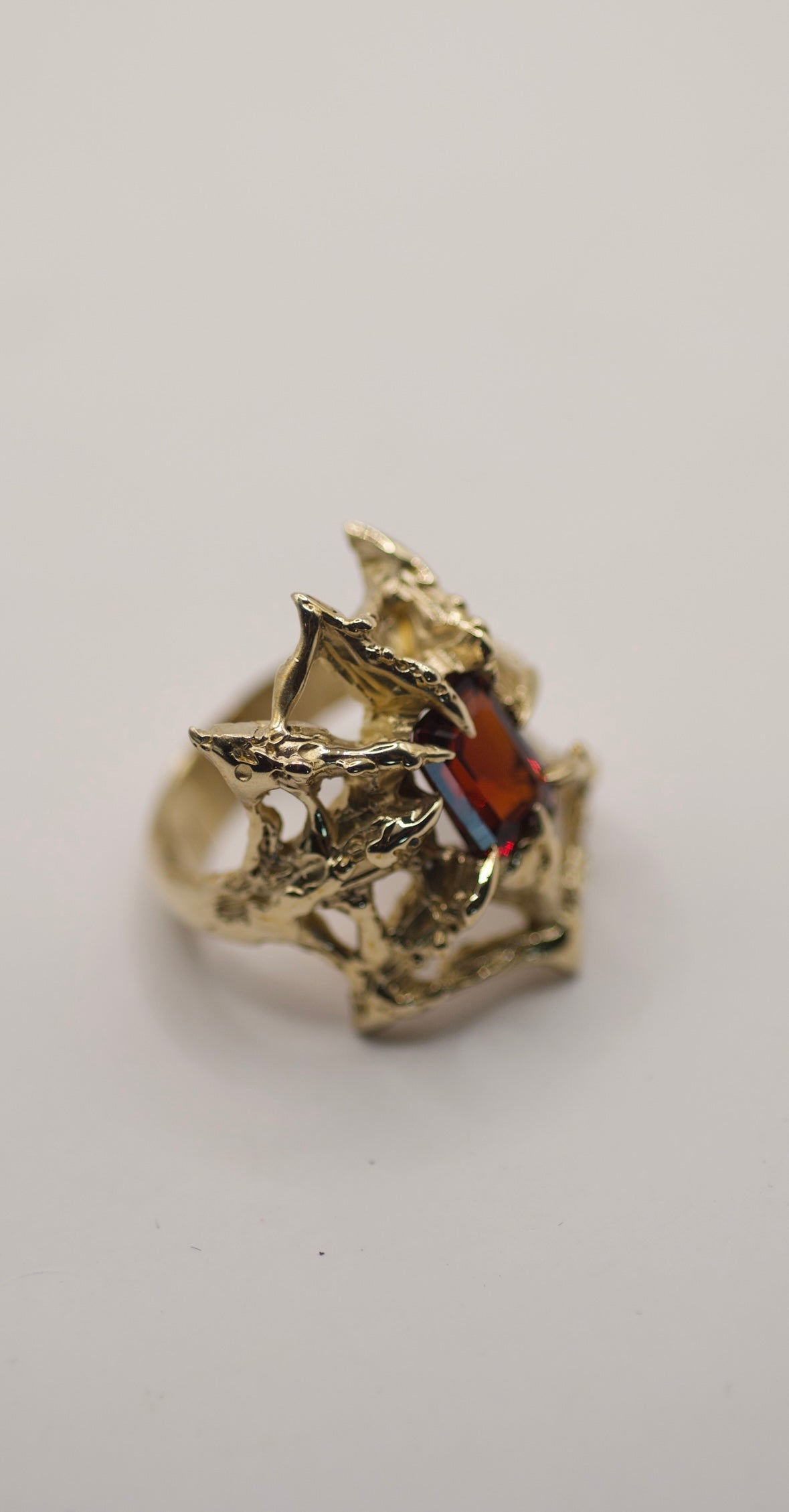 Handmade lost wax cast gold ring with intricate web structure surrounding a lab-grown red garnet, bold gothic inspired alternative ring made using the wax carving technique