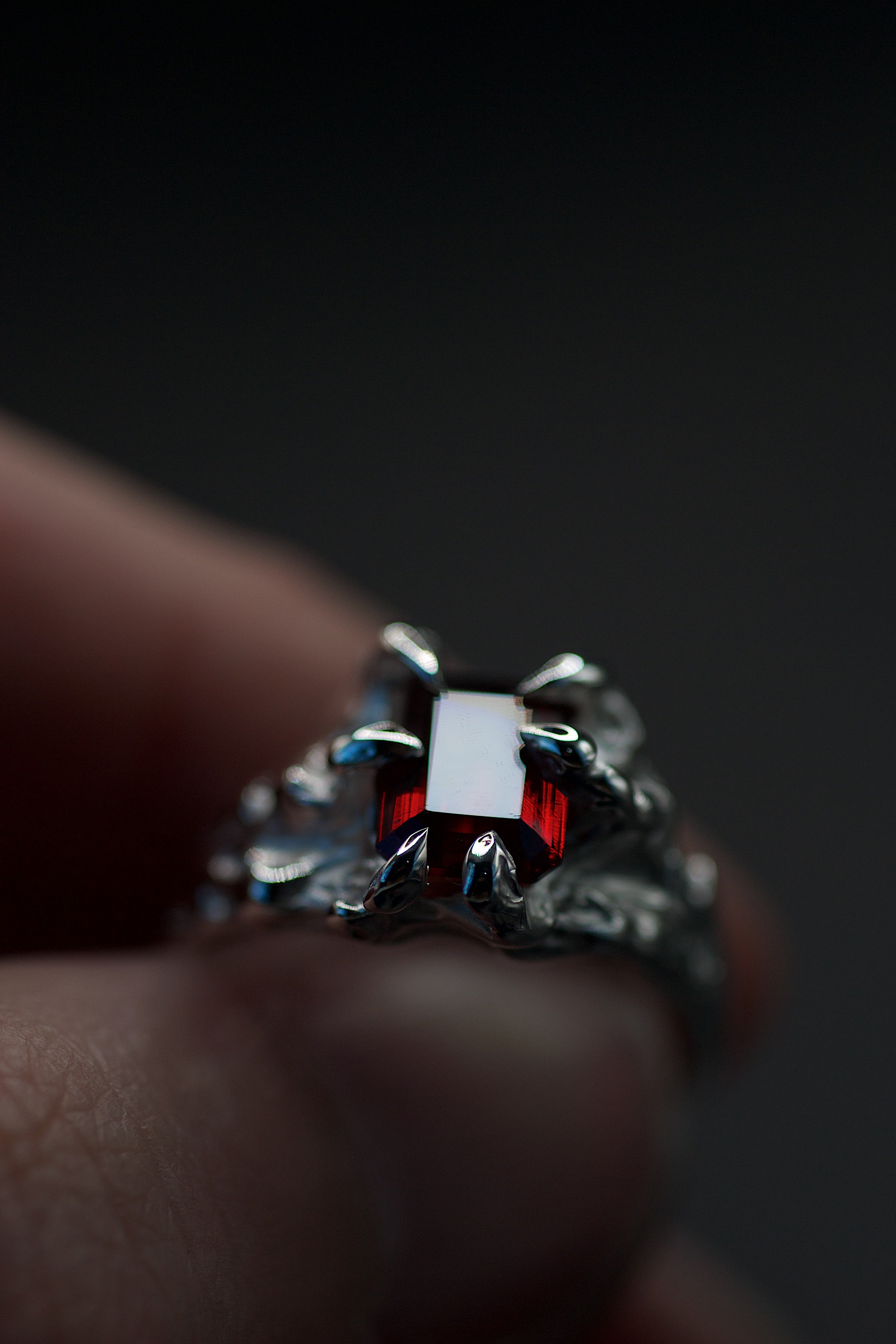 Lost wax cast silver Dragon Ring with red lab-grown crystal held in hand against dark background handmade gothic alternative ring made using the wax carving technique