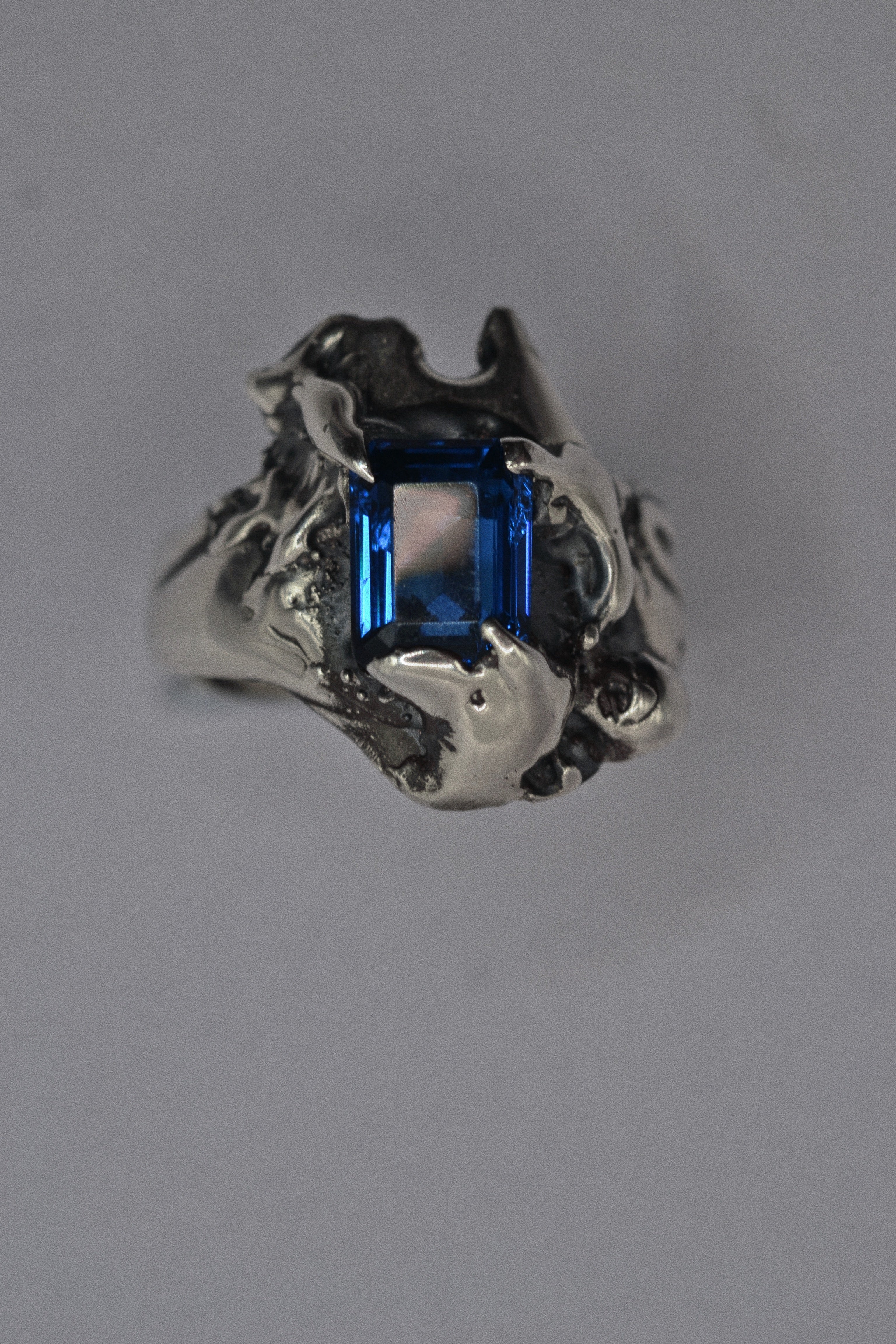 Front view of the Infinity Ring showing lab-grown blue sapphire within extreme organic sculptural sterling silver forms lost wax cast