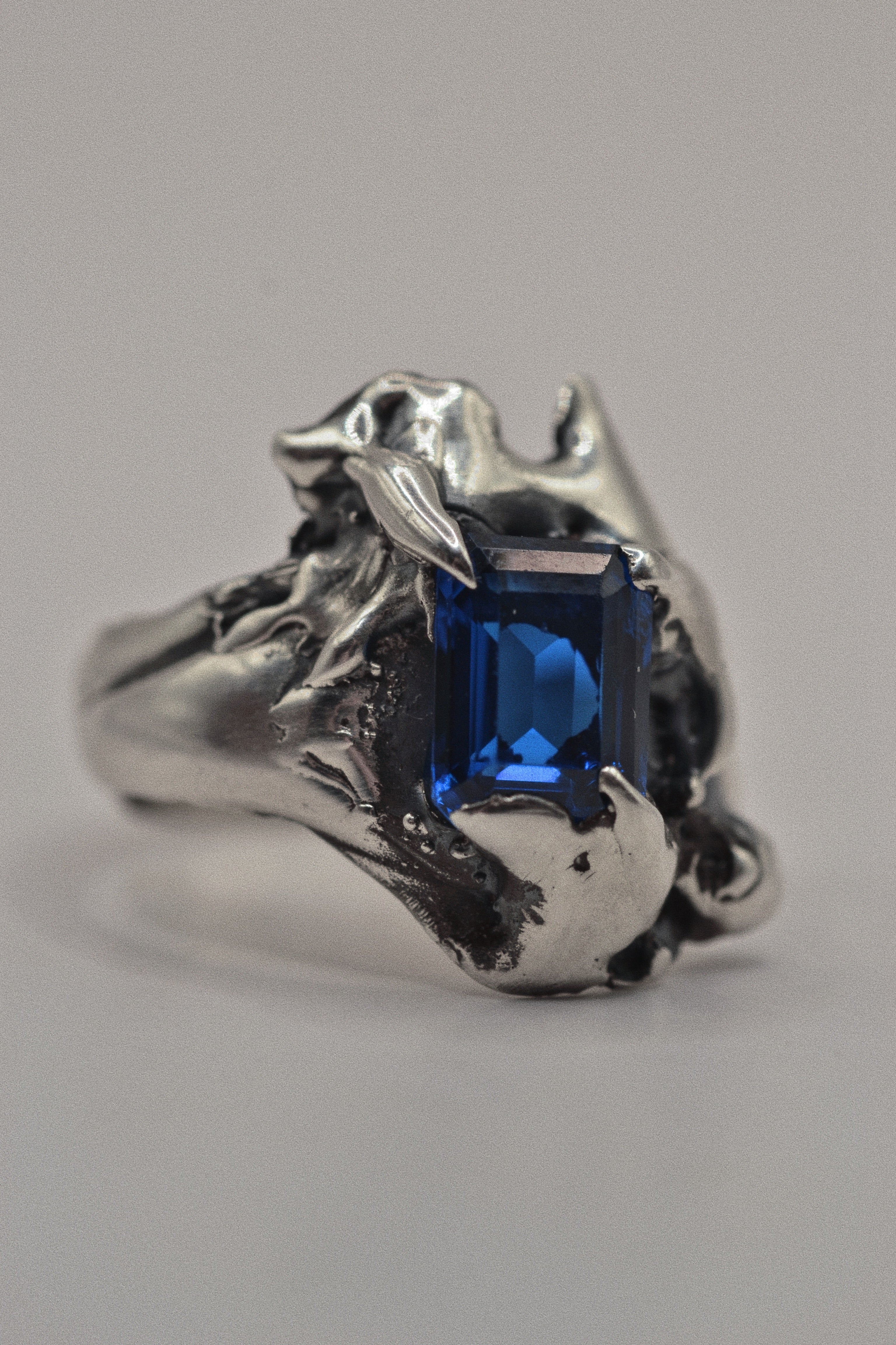 Handmade lost wax cast sterling silver ring with extreme organic sculptural forms surrounding a lab-grown blue sapphire, bold alternative ring celebrating individuality made using the wax carving technique