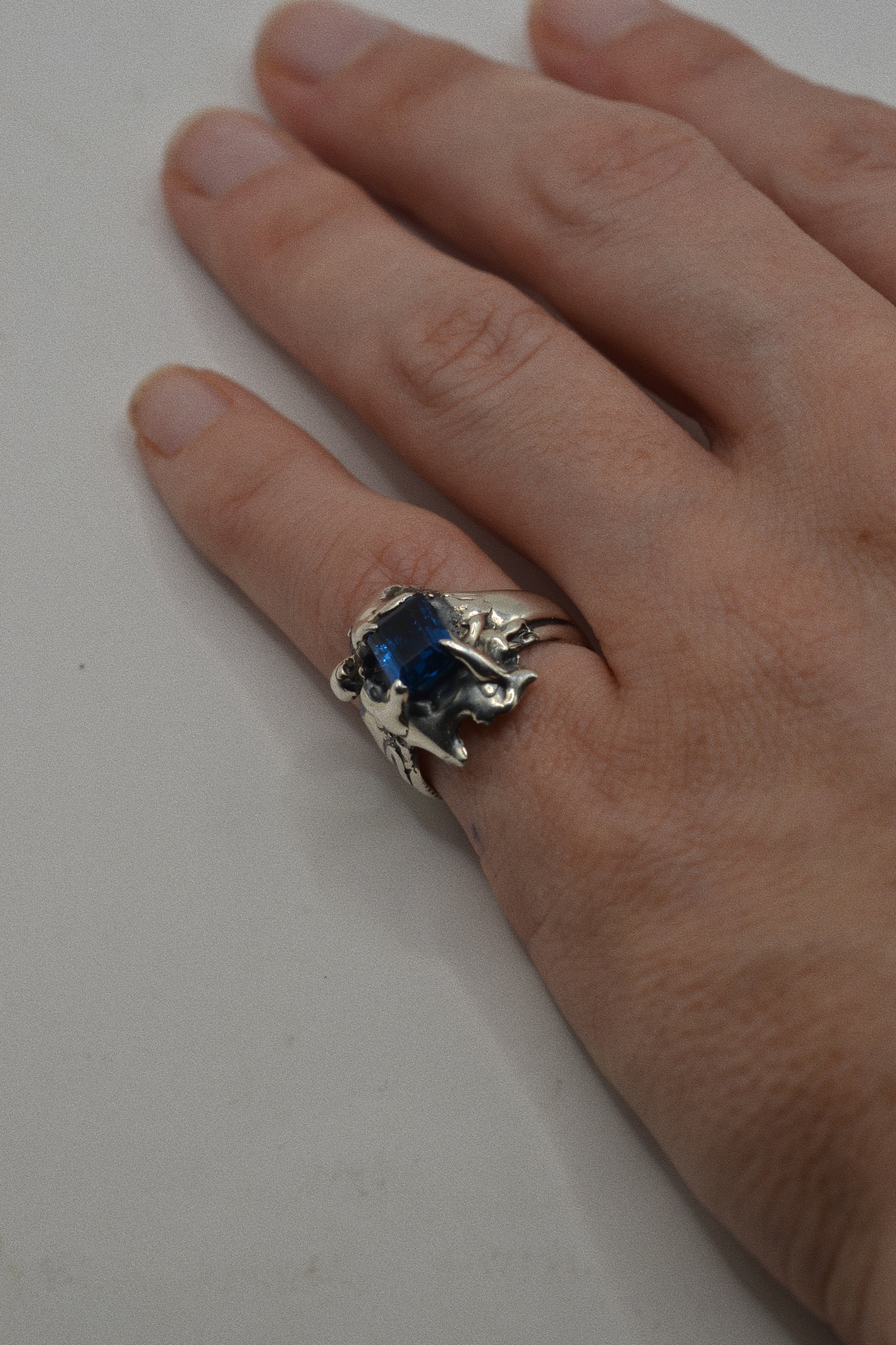 Lost wax cast silver Infinity Ring worn on hand with lab-grown blue sapphire and extreme organic sculptural silver forms