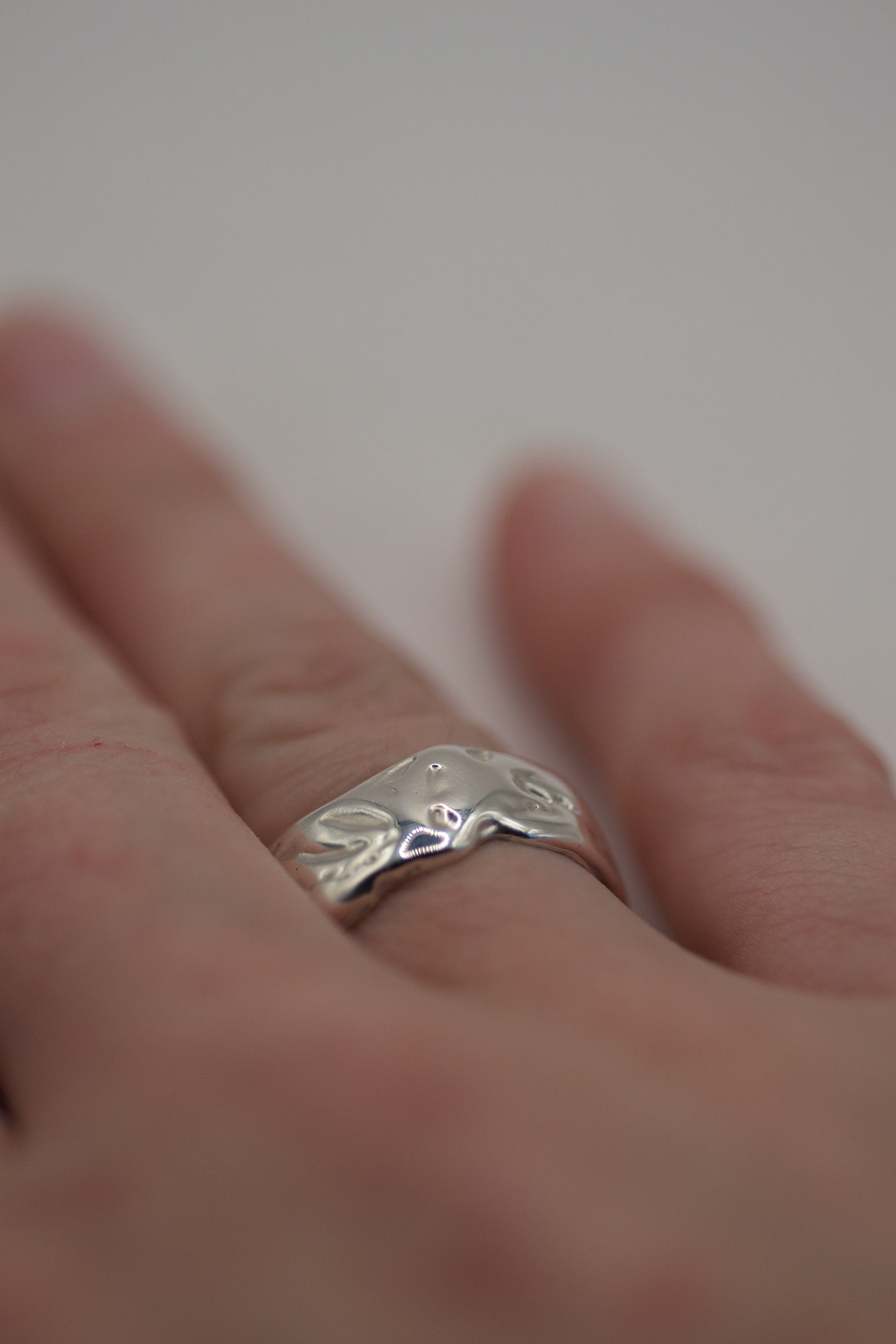 Third angle of the Molten Ring worn on hand showing simple organic molten sterling silver band handmade using the wax carving technique