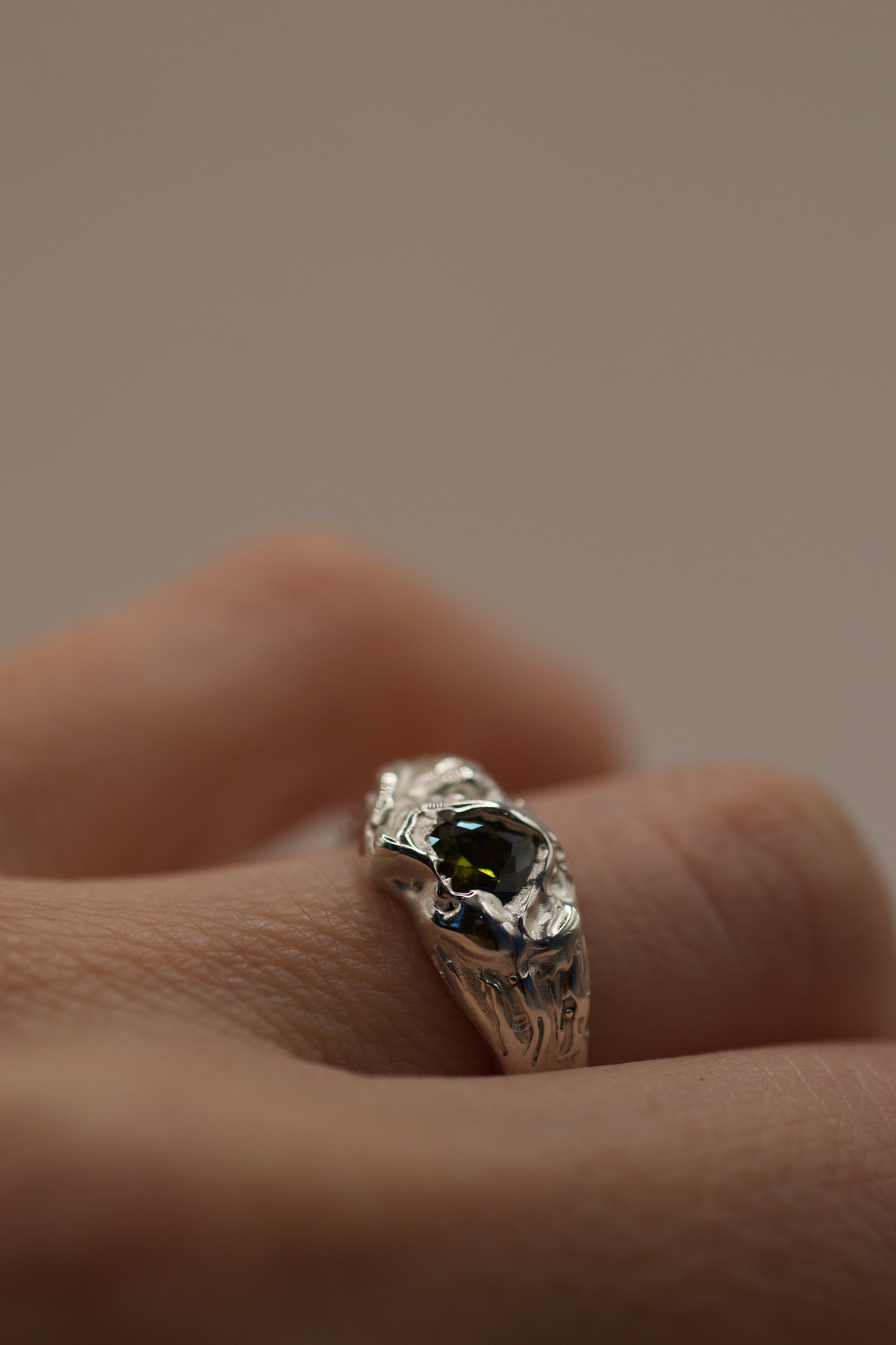 Lost wax cast silver Olive You Ring worn on hand with olive green heart cubic zirconia and organic textured molten silver setting