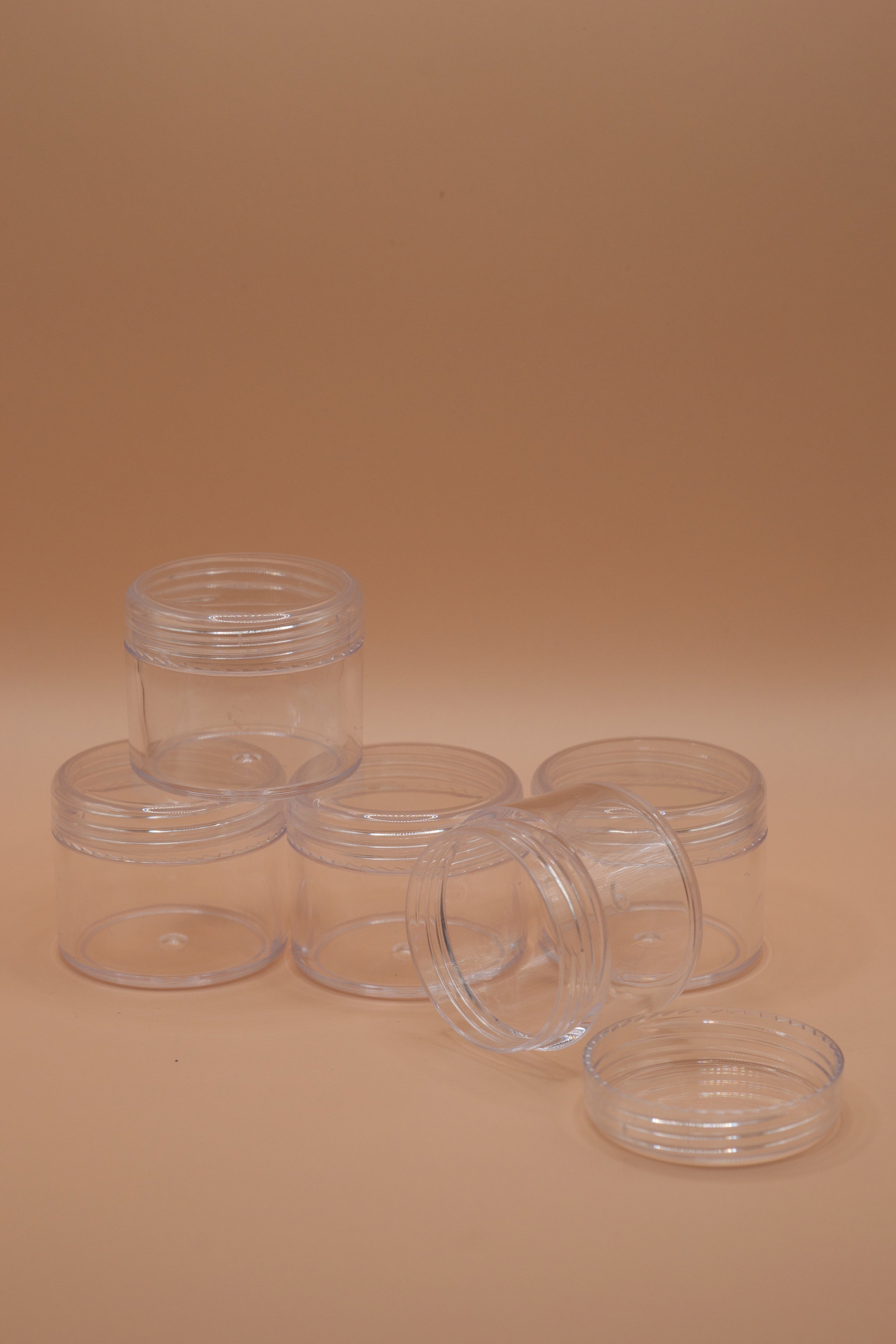 Transparent plastic jars shown stacked in a pyramid formation, ideal for storing and shipping wax jewellery models securely.