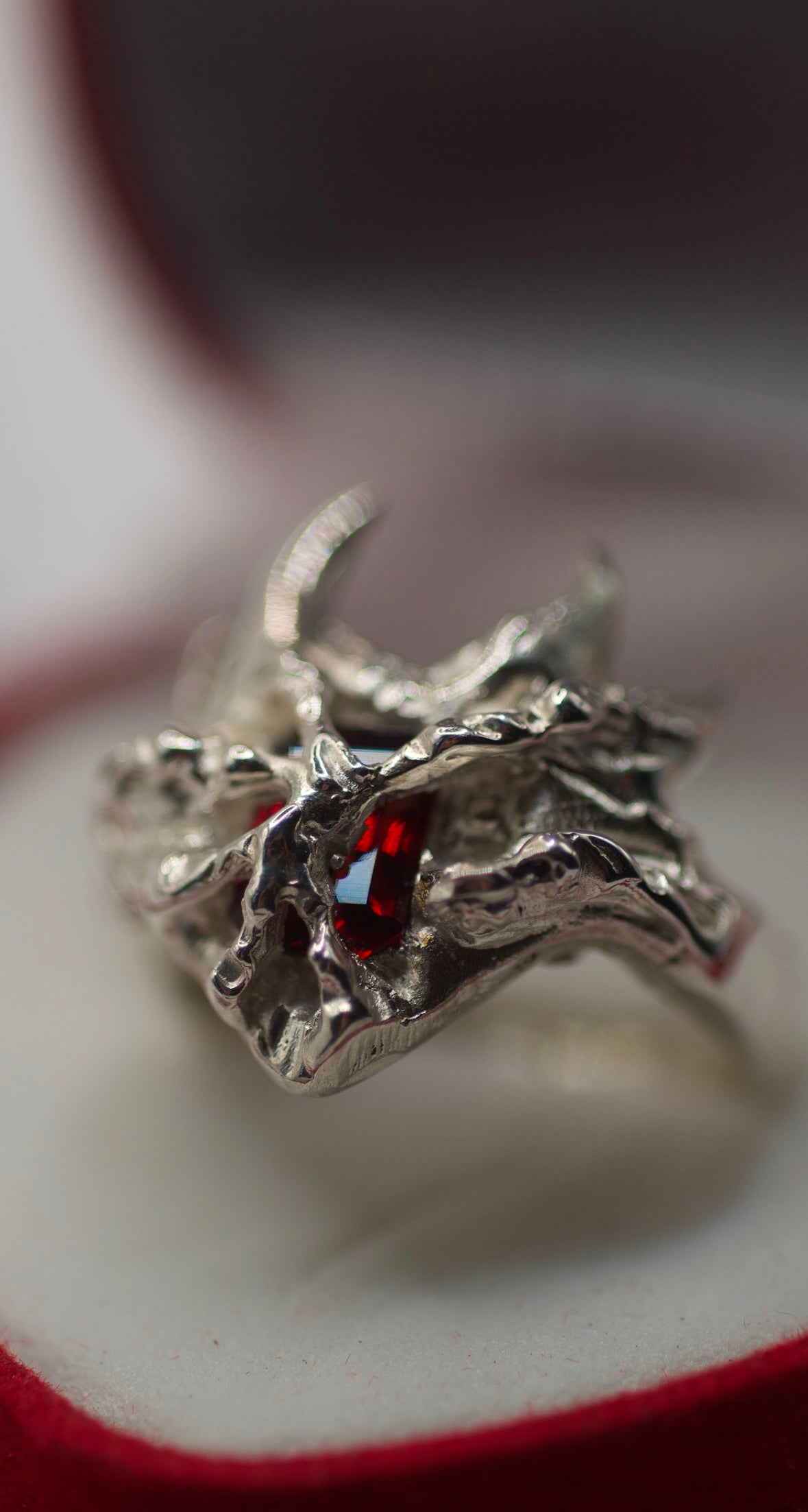 Handmade sterling silver ring created using the cast-in-place process with molten silver solidified directly over a red lab-grown garnet, fierce self-expression ring made using the wax carving technique