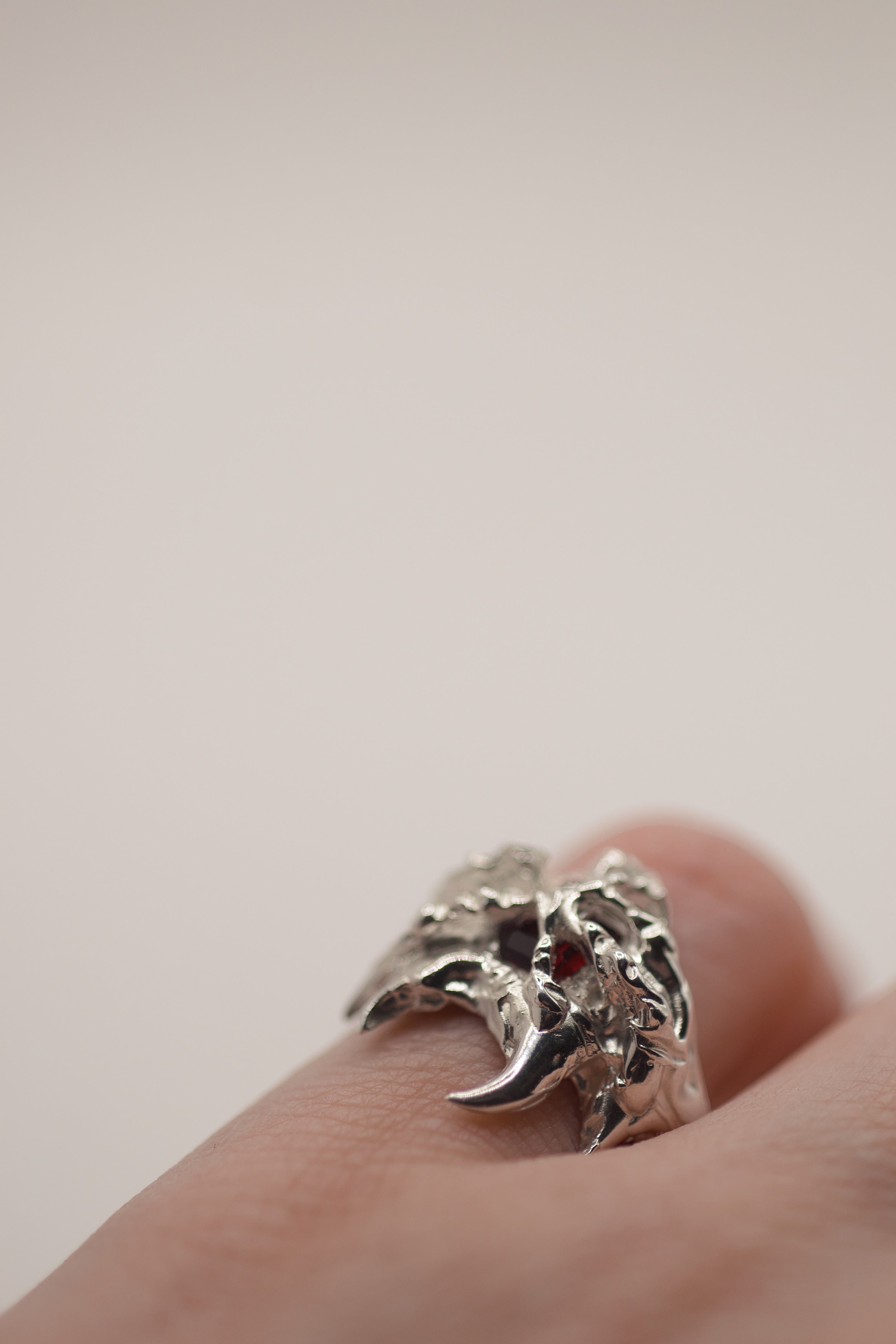 Sacred Ring worn on hand second shot showing red lab-grown garnet and raw organic layered sterling silver setting
