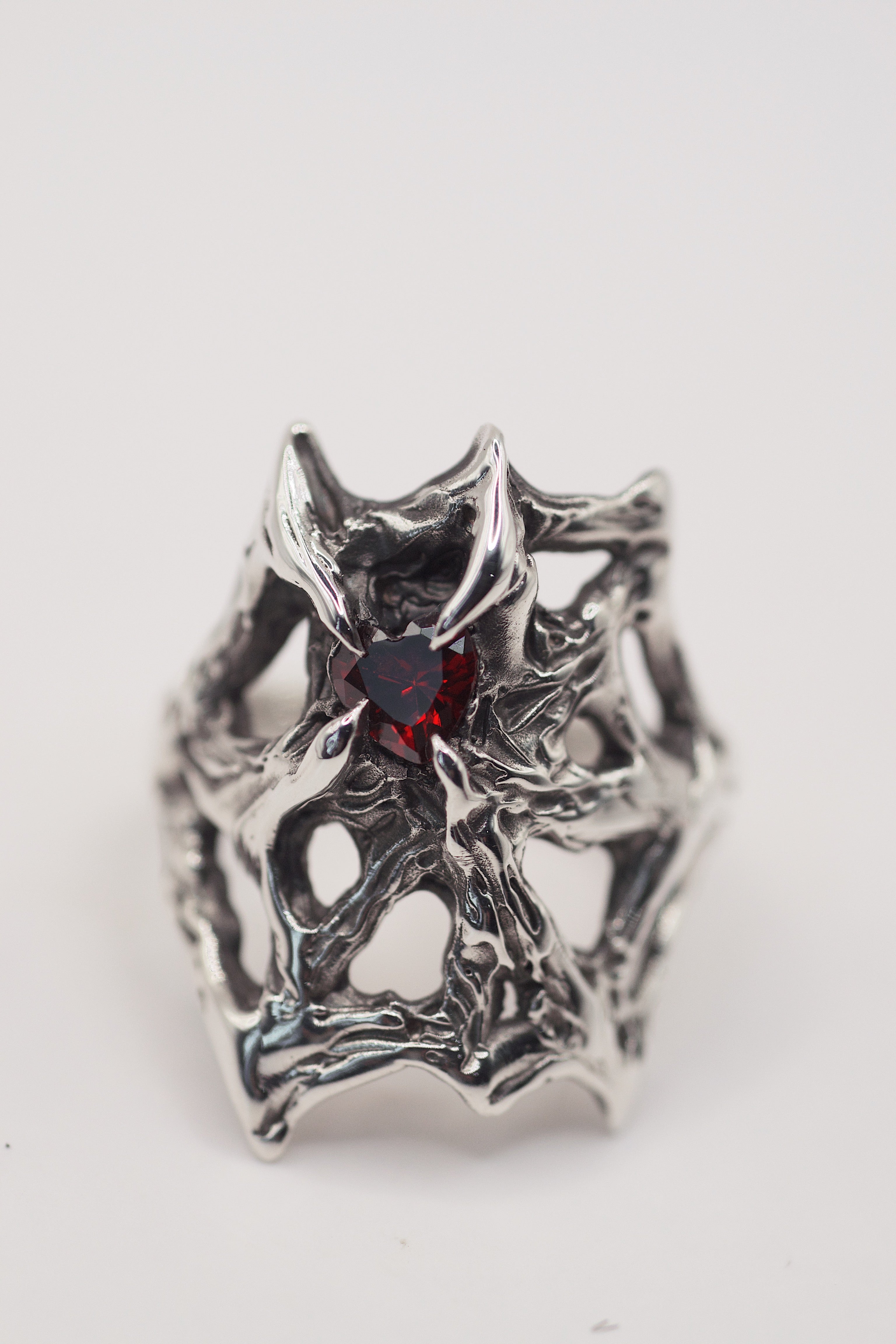 Lost wax cast darkened sterling silver Scarlet Ring worn on hand with intricate web structure and lab-grown red garnet heart