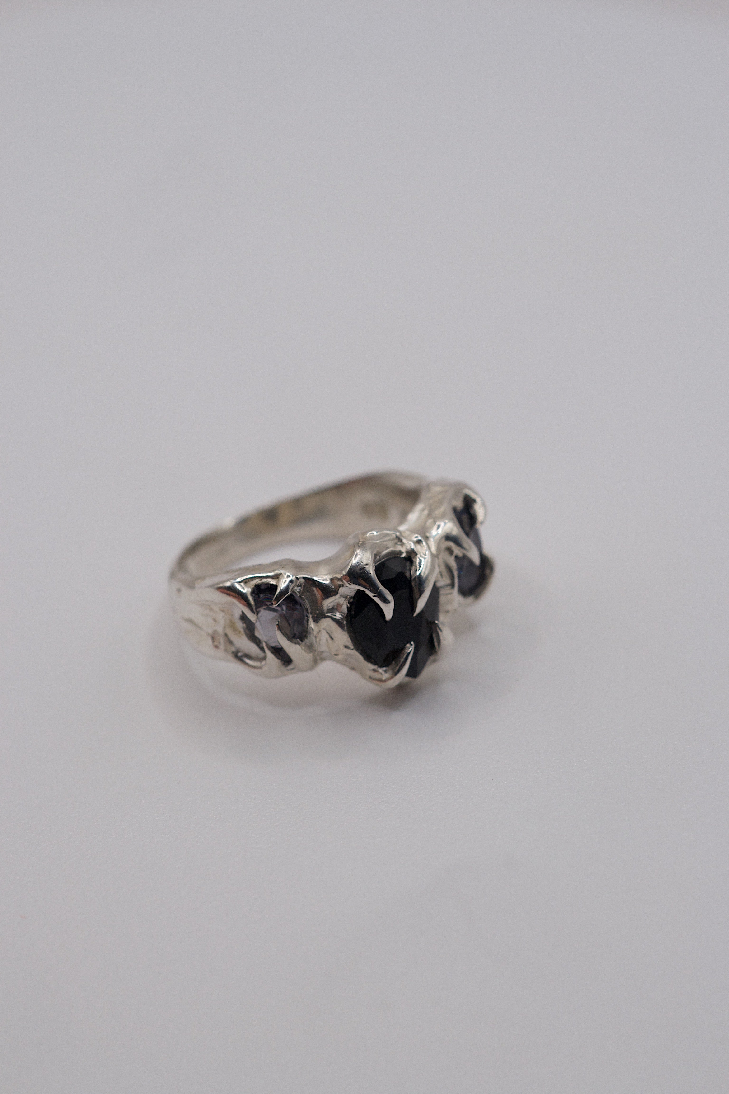 Top angled view of sterling silver ring with three pear-cut lab-grown gemstones featuring flowing gothic claws.