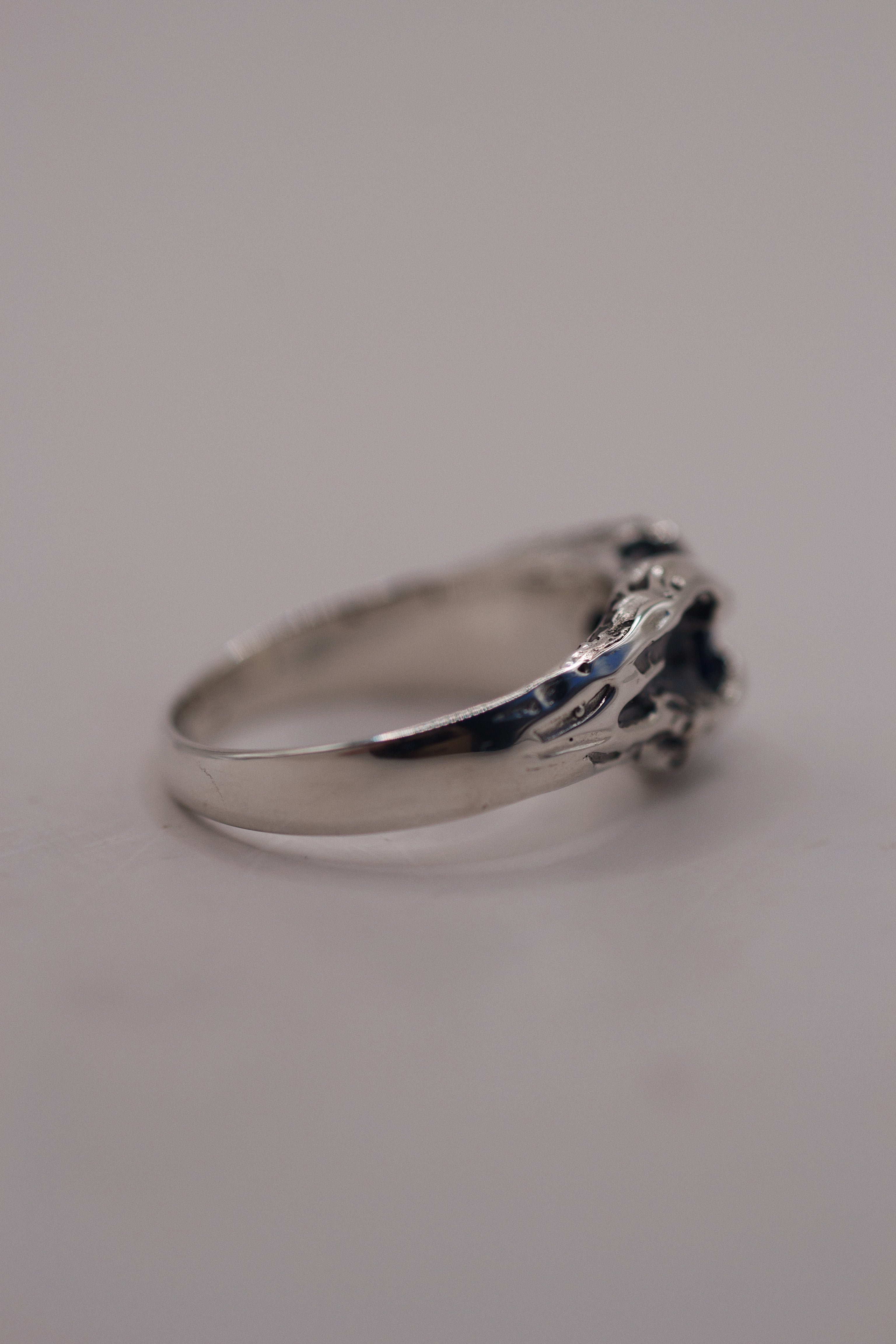 Flat view of the Volcanic Ring showing darkened recycled sterling silver band and blue natural sapphire with organic molten claw setting