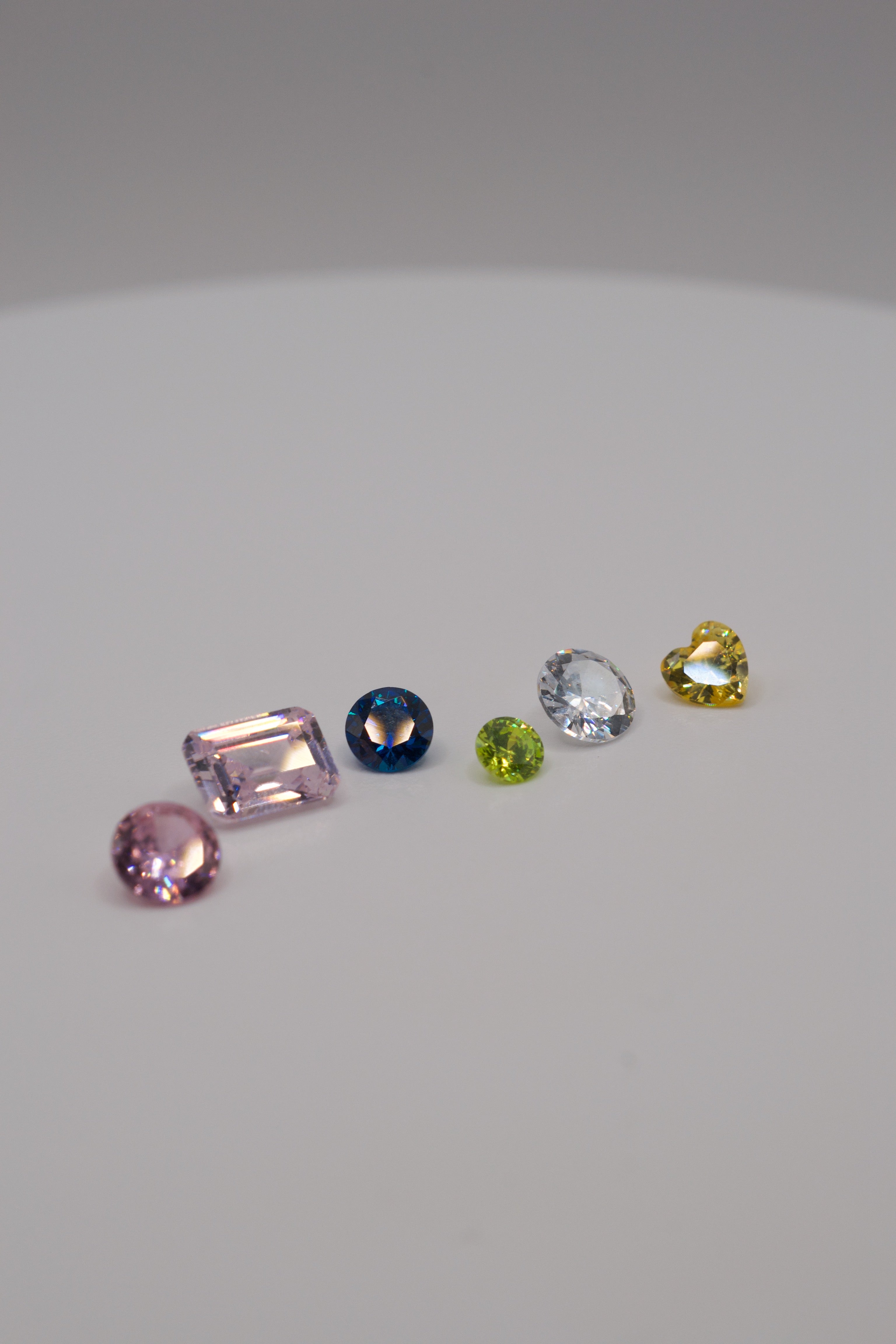 Selection of lab-grown and natural gemstones suitable for lost wax jewellery making, shown in various cuts and colours for cast-in-place and stone setting.