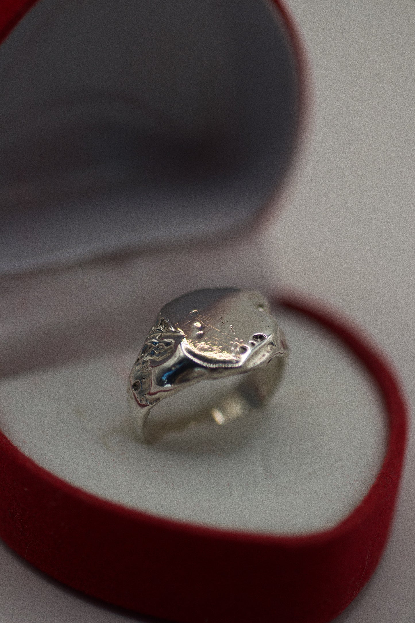 This 925 sterling silver signet ring is crafted with an organic, textured surface that features natural dips, grooves, and imperfections. The band is smooth and sleek, contrasting with the rougher, sculpted areas that create a rugged, earthy aesthetic. The ring’s flat surface has craters and subtle indentations, enhancing its unique, handmade look. Created using the lost wax method, this ring is as much a piece of art as it is a bold, wearable accessory.