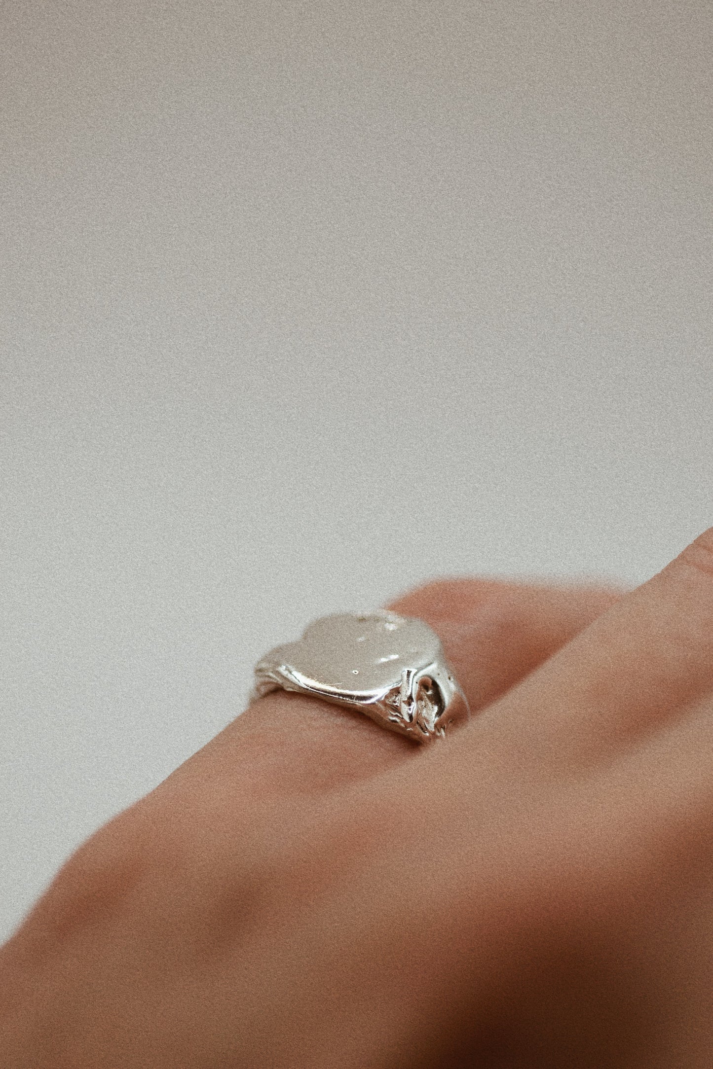 The 925 sterling silver signet ring features a textured surface with organic dips and grooves, providing an earthy, rugged finish. The ring's smooth band leads to the sculpted, uneven surface, where subtle craters add depth and complexity. Using the lost wax method, this ring is a unique, handmade piece that blends sleek elegance with a raw, grunge-inspired look.