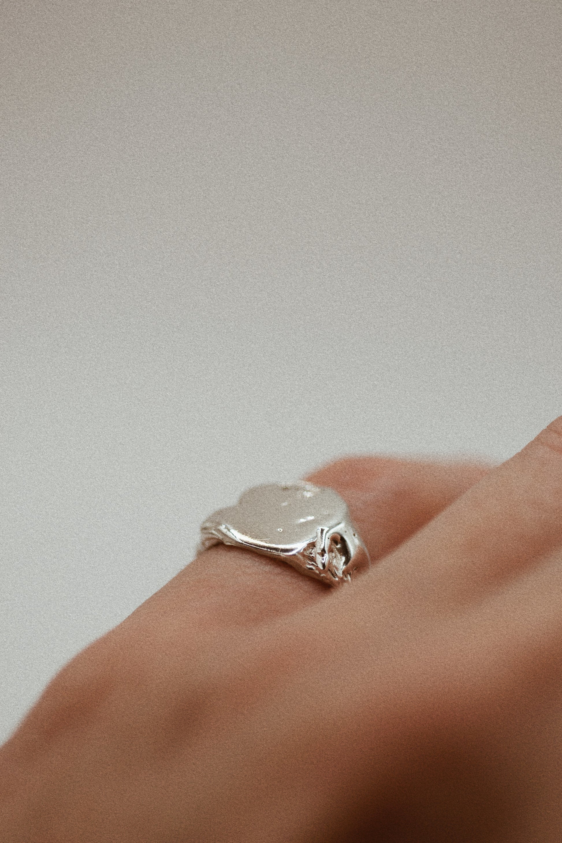 The 925 sterling silver signet ring features a textured surface with organic dips and grooves, providing an earthy, rugged finish. The ring's smooth band leads to the sculpted, uneven surface, where subtle craters add depth and complexity. Using the lost wax method, this ring is a unique, handmade piece that blends sleek elegance with a raw, grunge-inspired look.