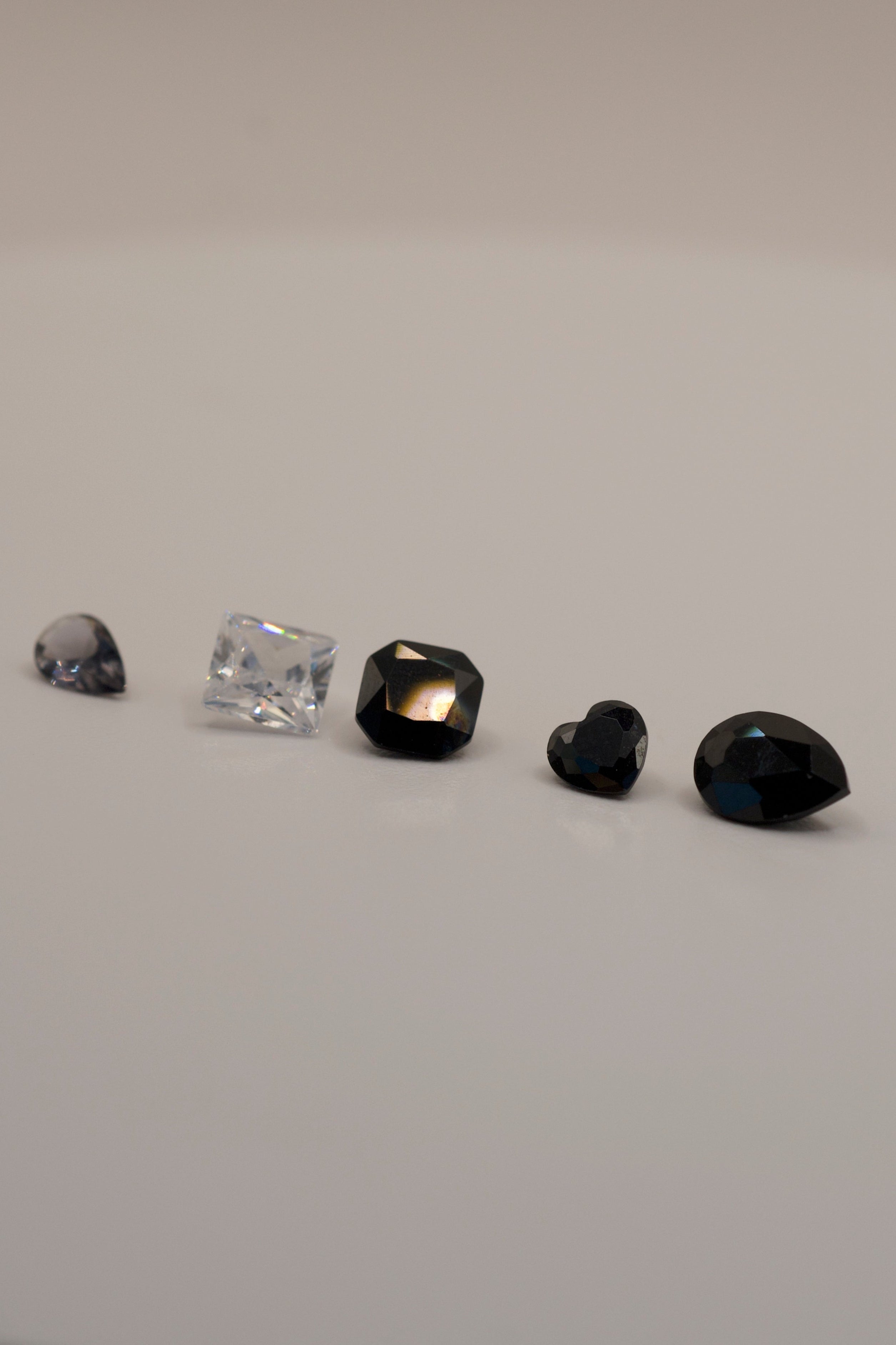 Loose faceted gemstones for lost wax casting in place, featuring black and clear stones in unique shapes for DIY rings and pendants.