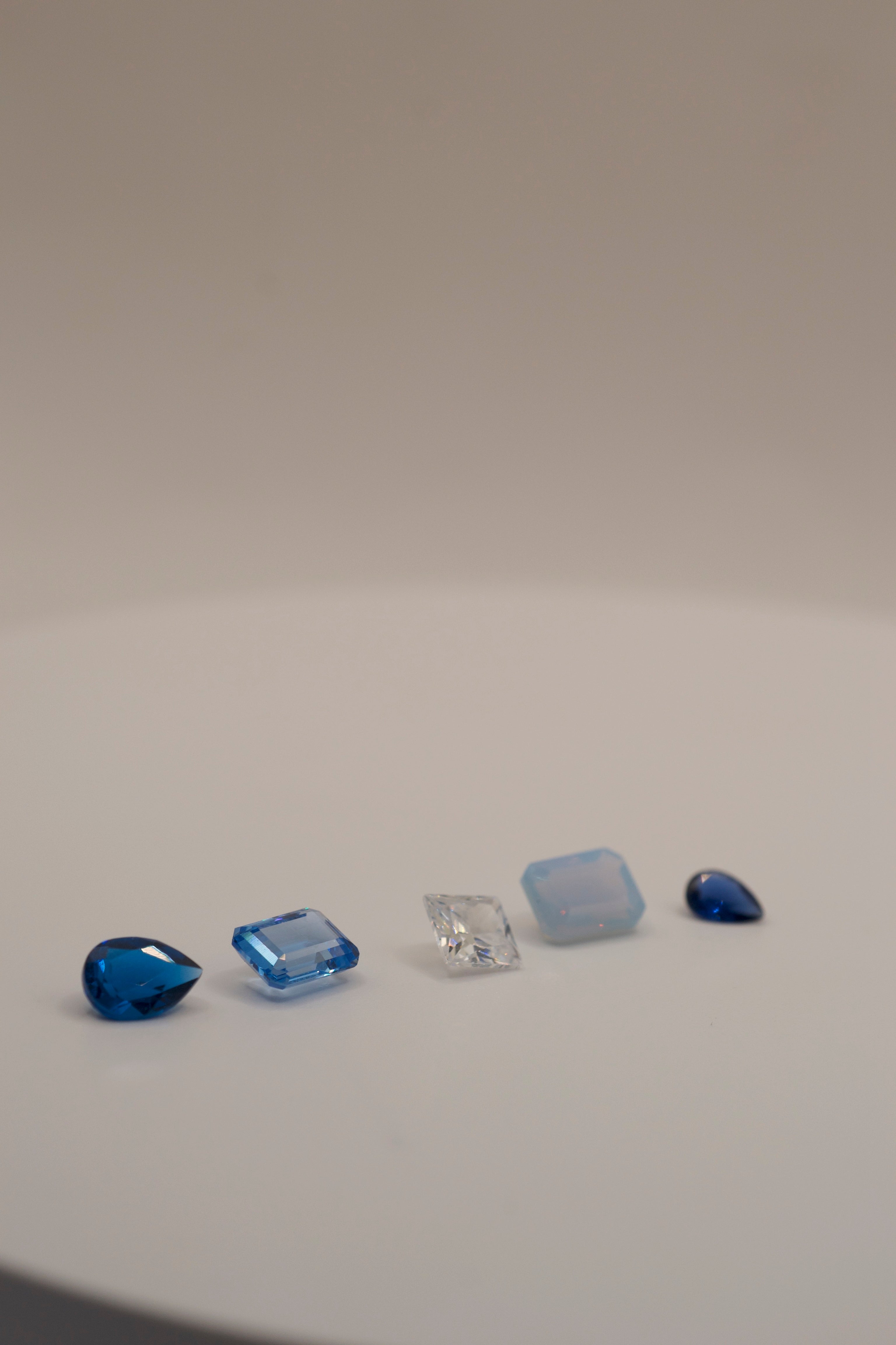 Jewellery making gemstones for lost wax casting – pear shape navy blue gemstone, emerald cut aqua stone, radiant cut white cubic zirconia, rectangular cut opal nano crystal, and trillion cut cobalt blue gem. Lab grown, heat resistant, ethical cast in place stones.