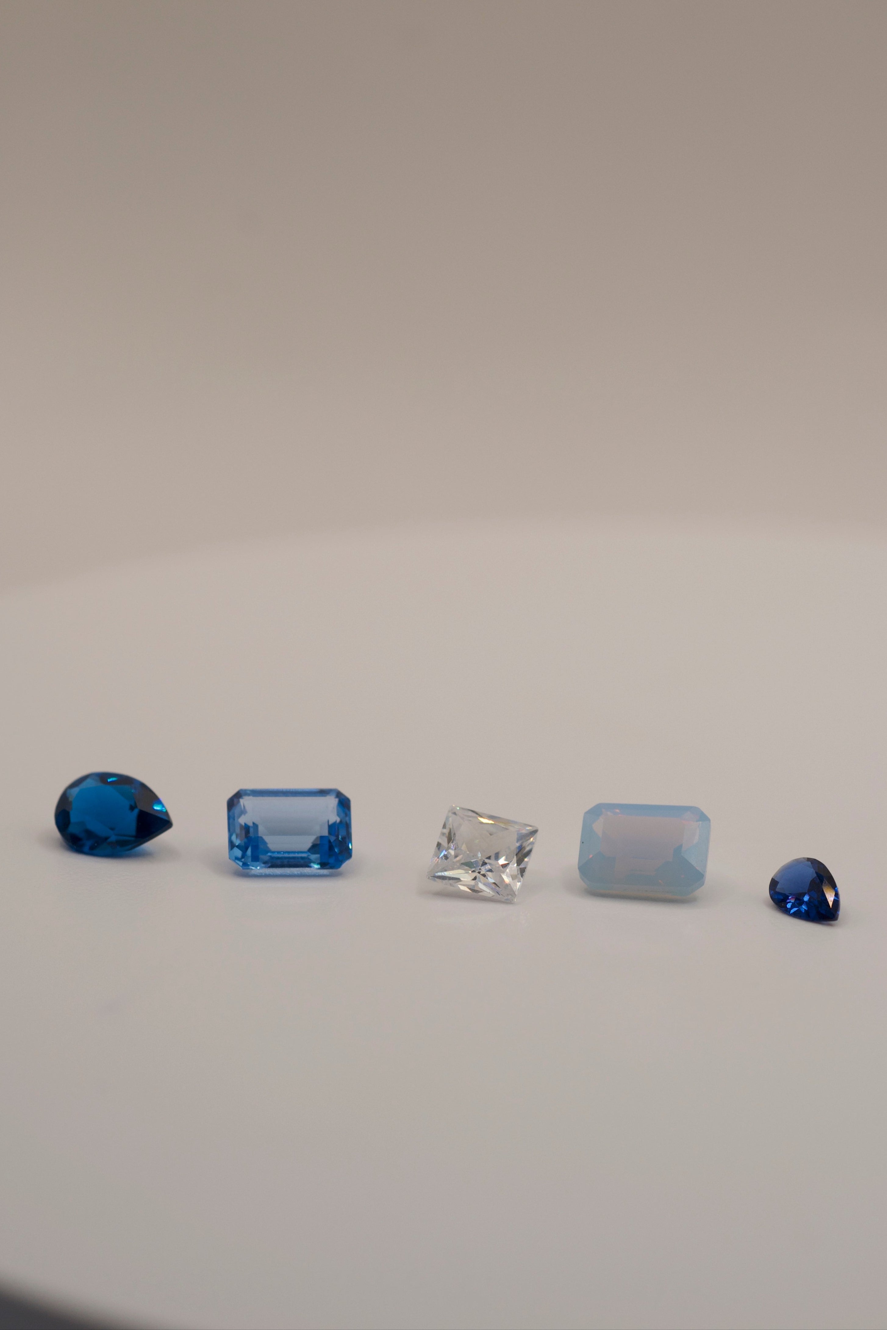 Cast in place gemstones for lost wax casting jewellery – pear cut deep blue gemstone, emerald cut light blue gemstone, radiant cut white cubic zirconia, emerald cut opal nano crystal, and trillion cut royal blue gemstone. Lab-grown, ethical gemstones perfect for jewellery making and lost wax casting.