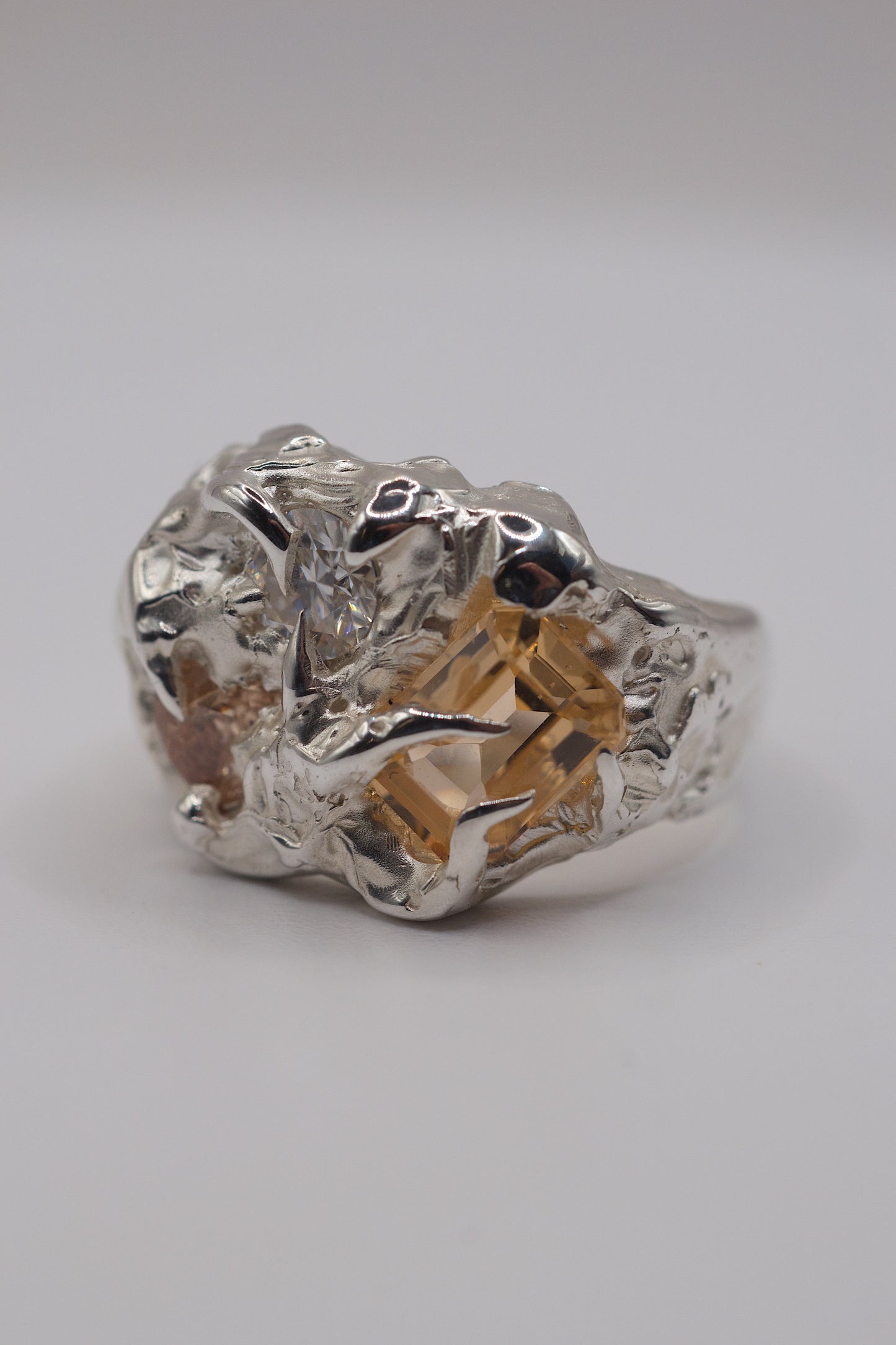 Molten sterling silver ring with white and yellow crystals with sharp prongs.