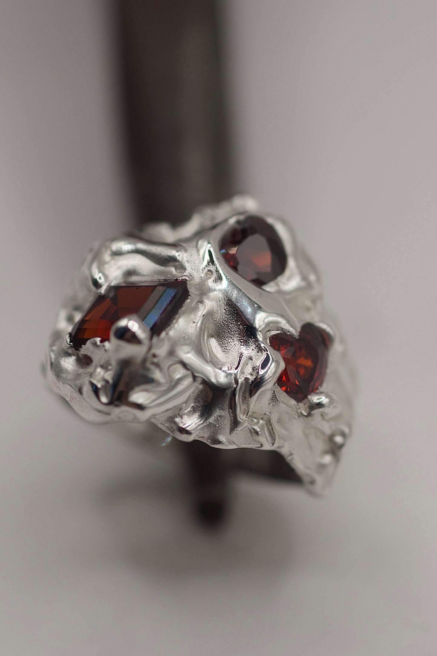 Silver ring with red gemstones on a gray background